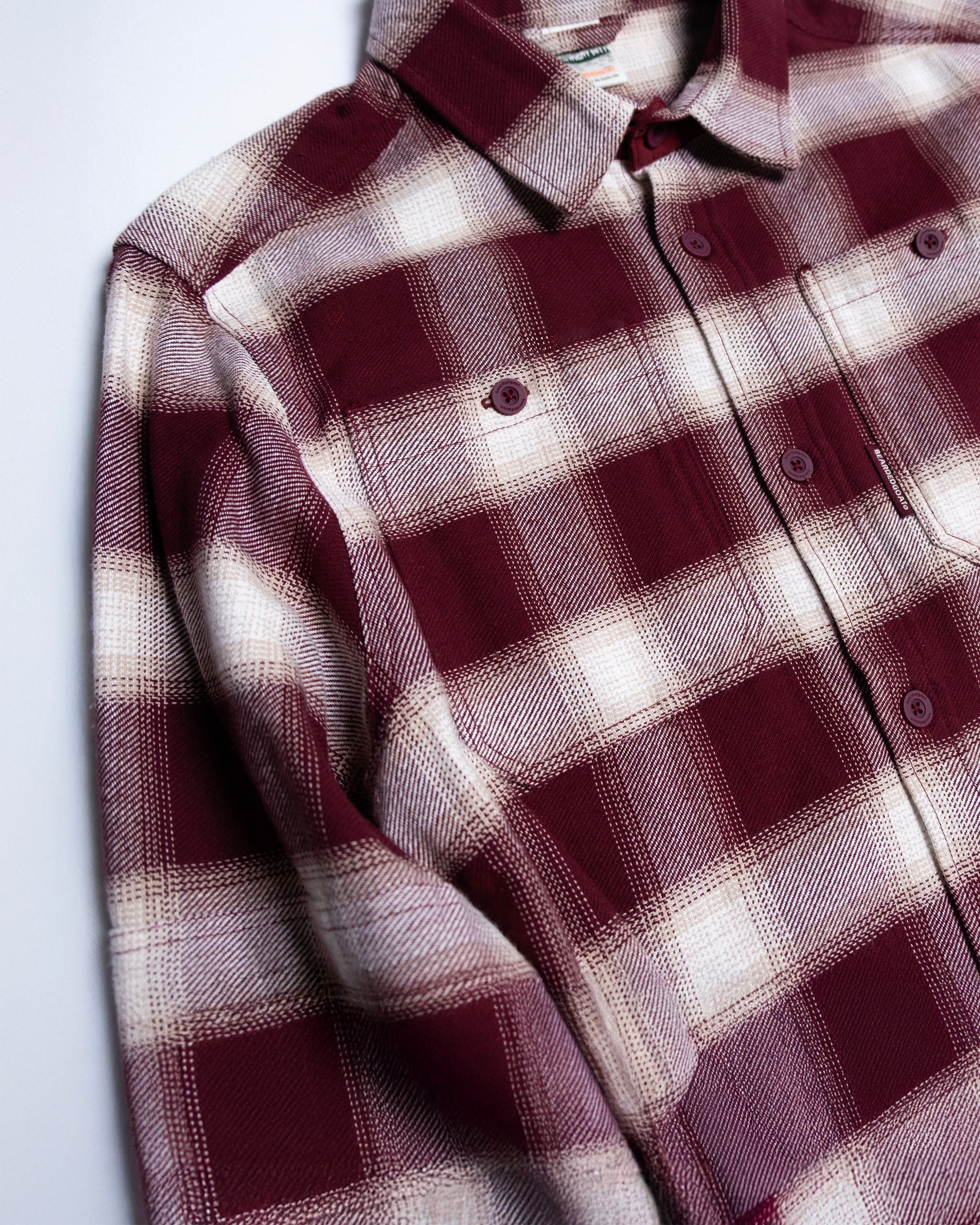 The beardedgoat NEW--Ozark Utility Flannel™ is a cranberry heavyweight plaid workwear shirt with buttons and a chest pocket, shown laid flat on a white surface.