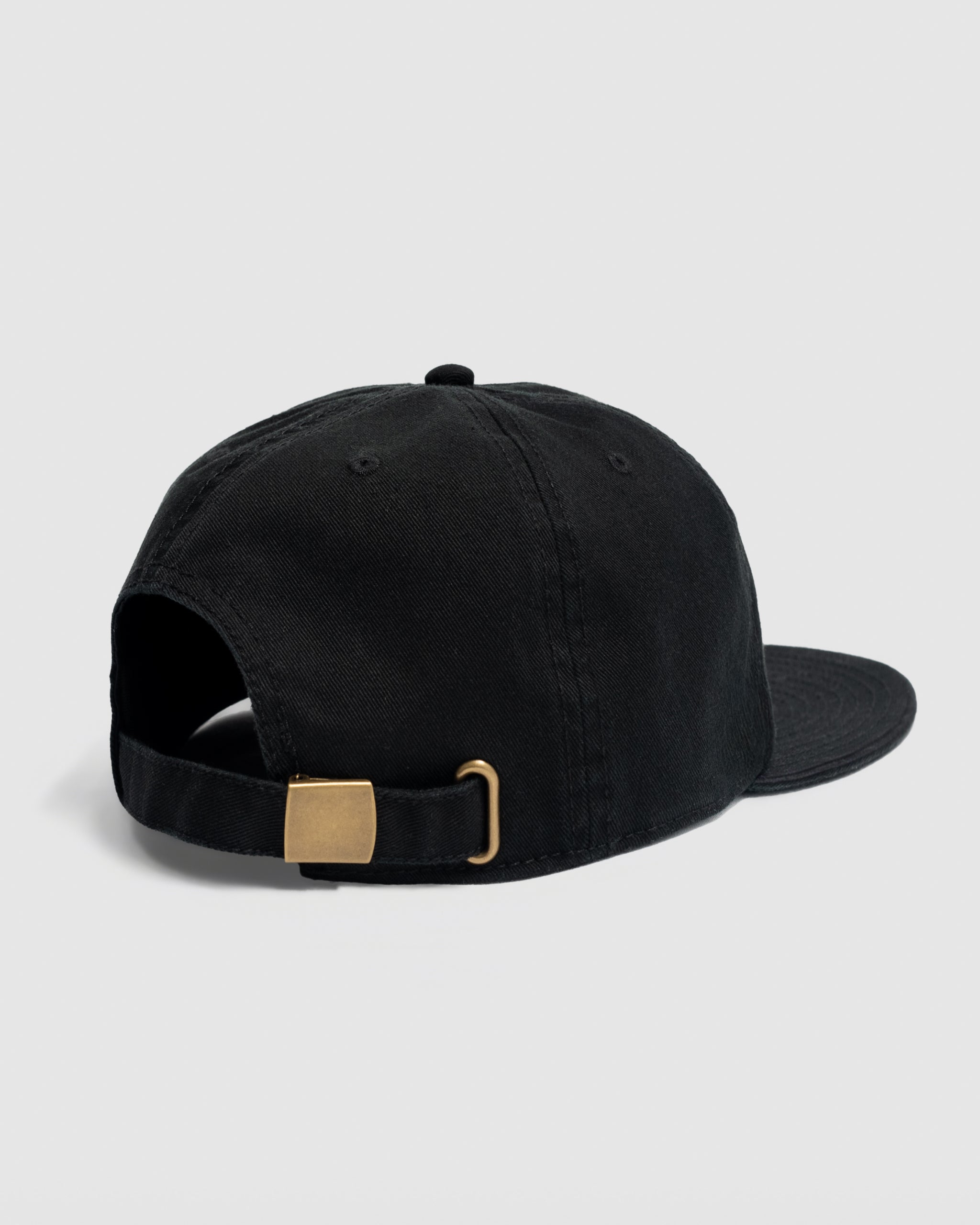 The BEARDEDGOAT Elements Hat - Black is shown from the back, highlighting its adjustable strap with brass buckle. Ideal for outdoor style, set against a plain light gray background.