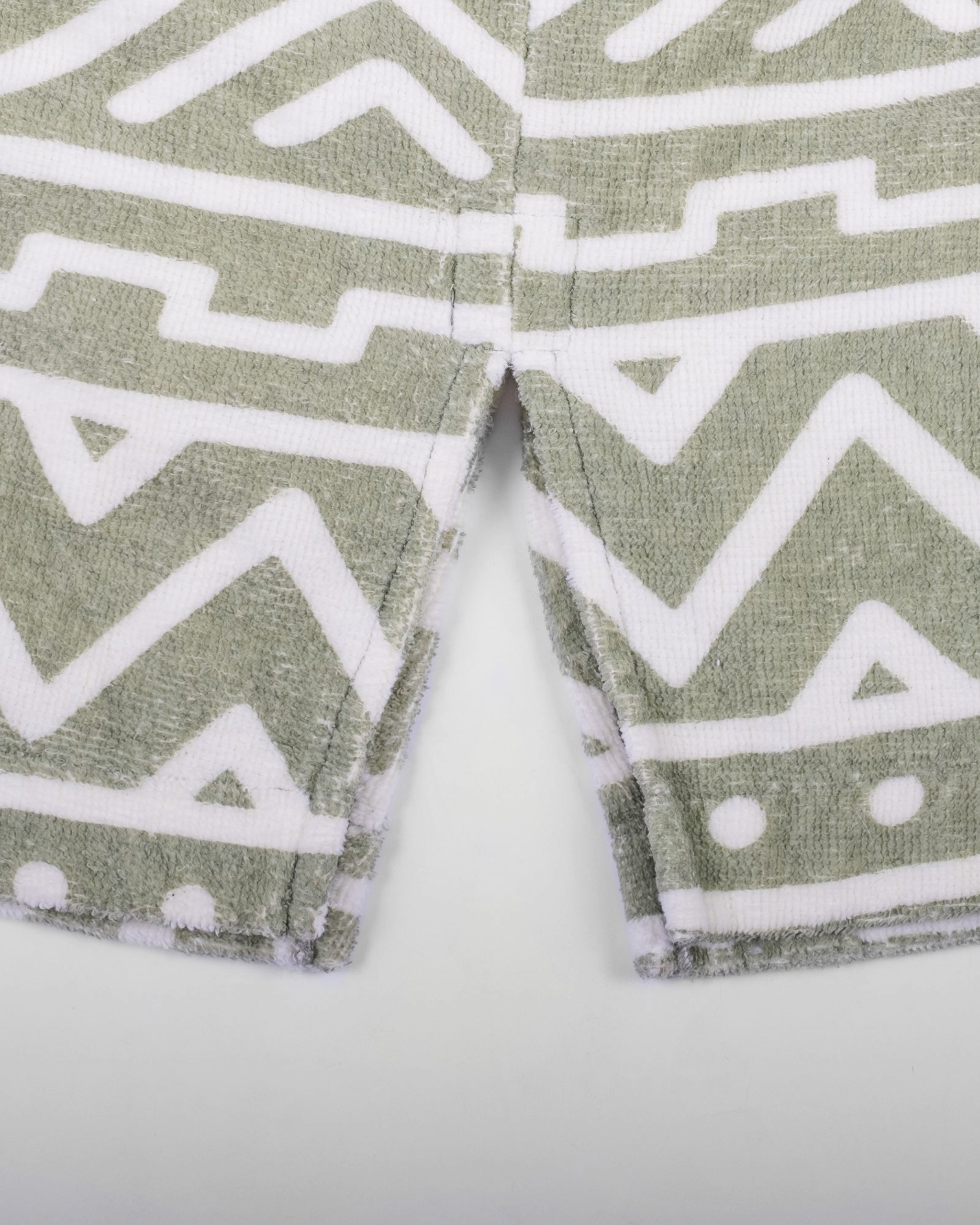 Close-up of a beardedgoat Changing Towel fabric with green and white geometric patterns—zigzags, lines, and dots. The central slit highlights the bold double-sided design, making it perfect for your summer adventures.