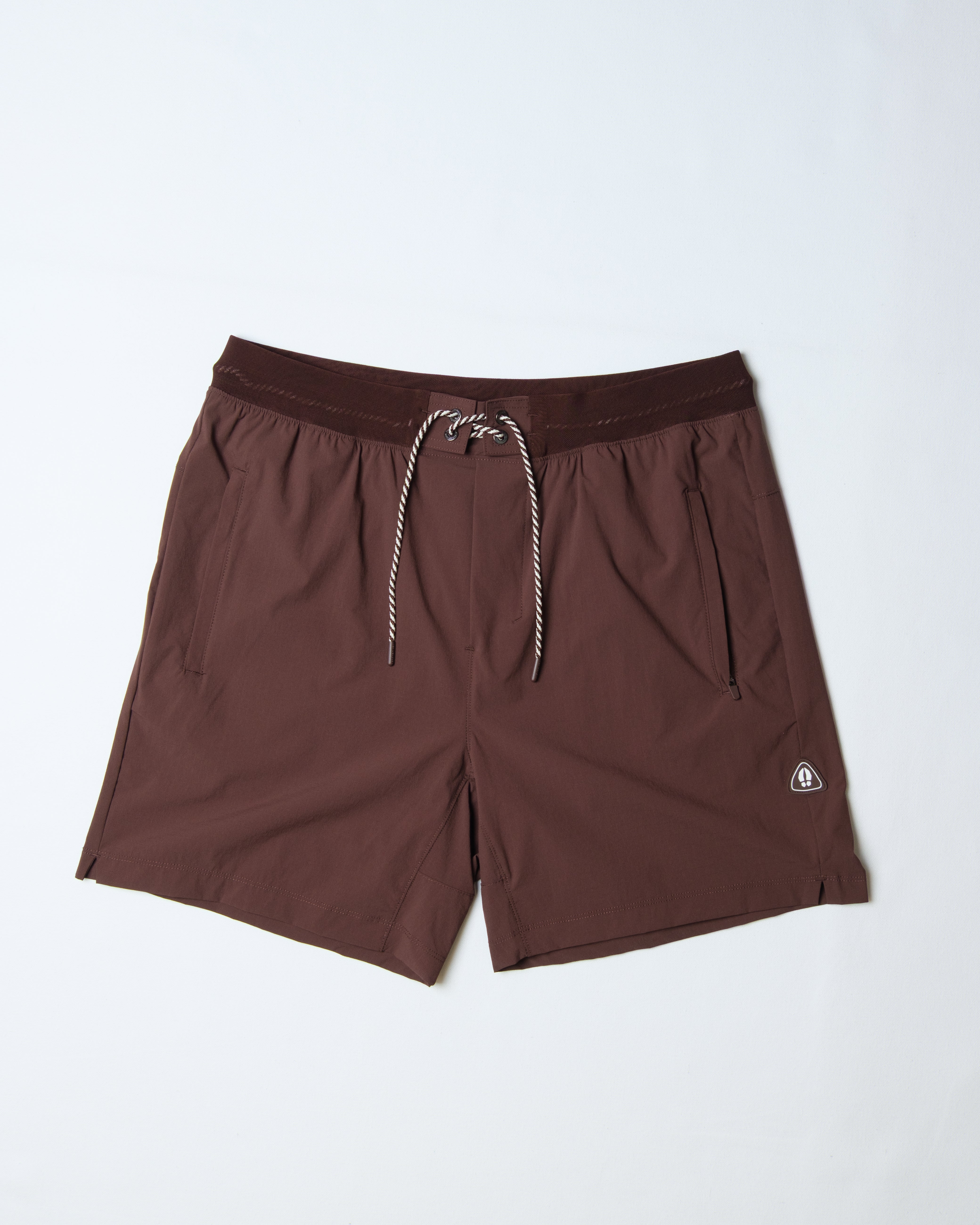 The BEARDEDGOAT Men's Rambler Short, in brown, features 4-way stretch fabric, an adjustable drawstring waist, two side pockets, and a small white logo—ideal for trail running and shown on a white background.