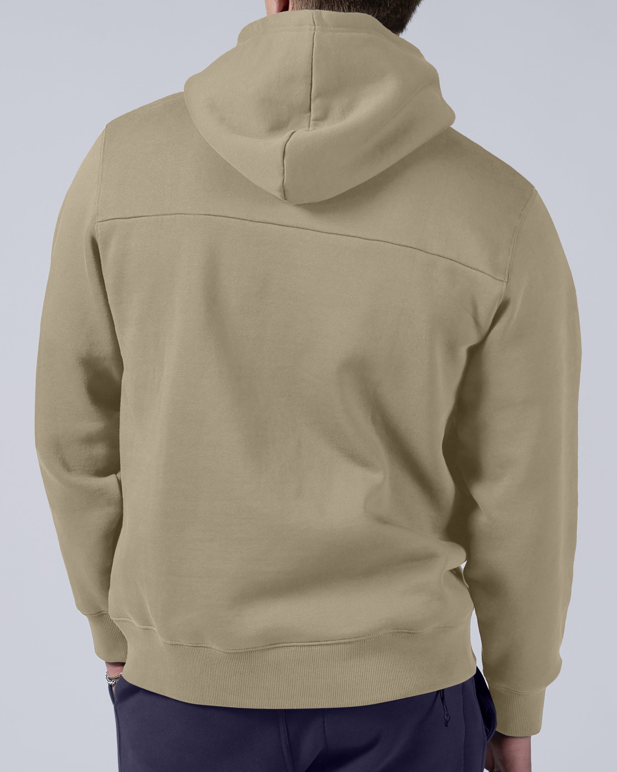 A man is seen from behind wearing the beardedgoat Men's Void Hoodie in beige with dark pants, standing against a plain light gray background.