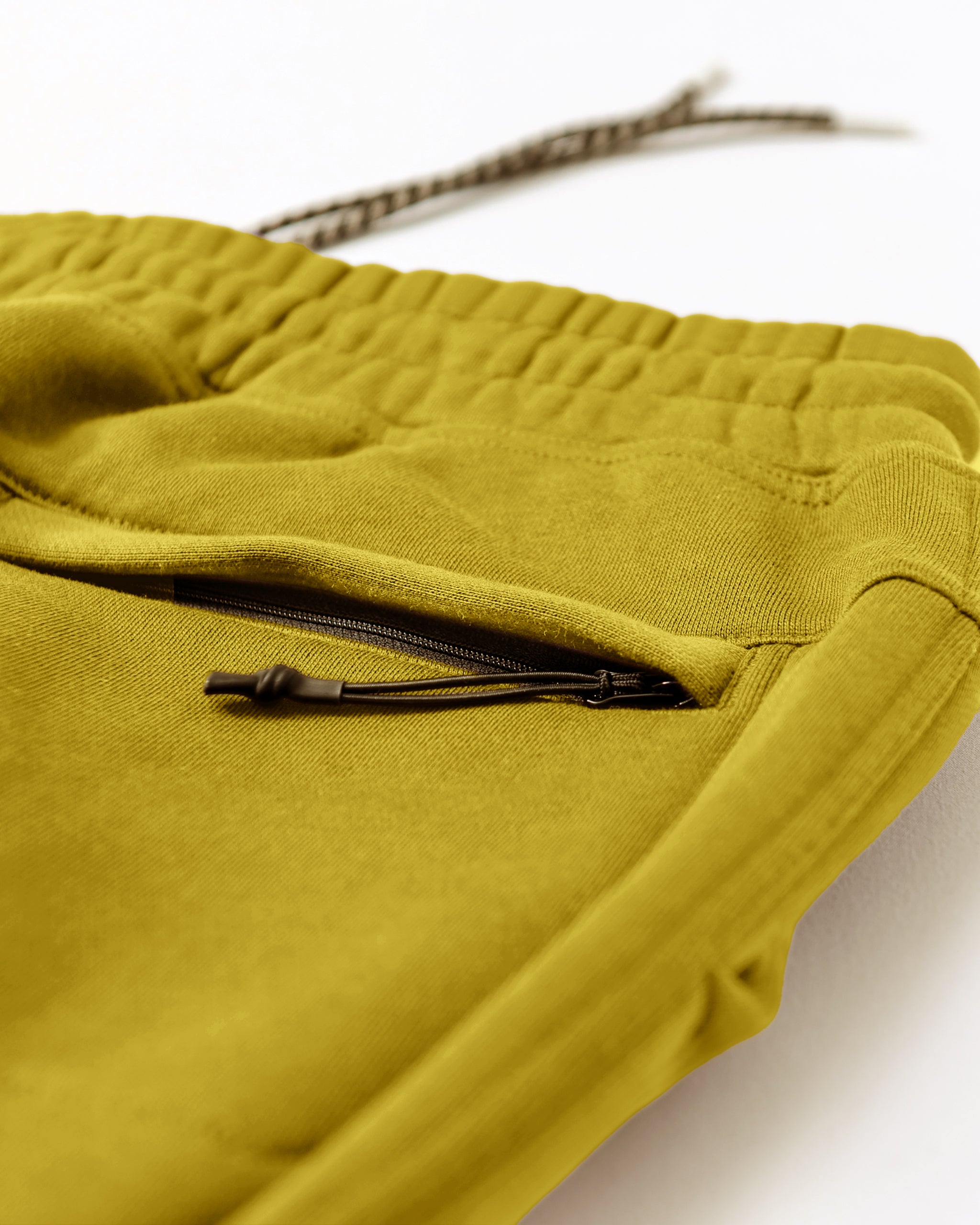 Close-up of the beardedgoat VOID™ Sweatpant in mustard yellow heavyweight fleece, featuring an elastic waistband, drawstring, and zippered pocket with black pull. Made from premium cotton for softness, comfort, and durability.