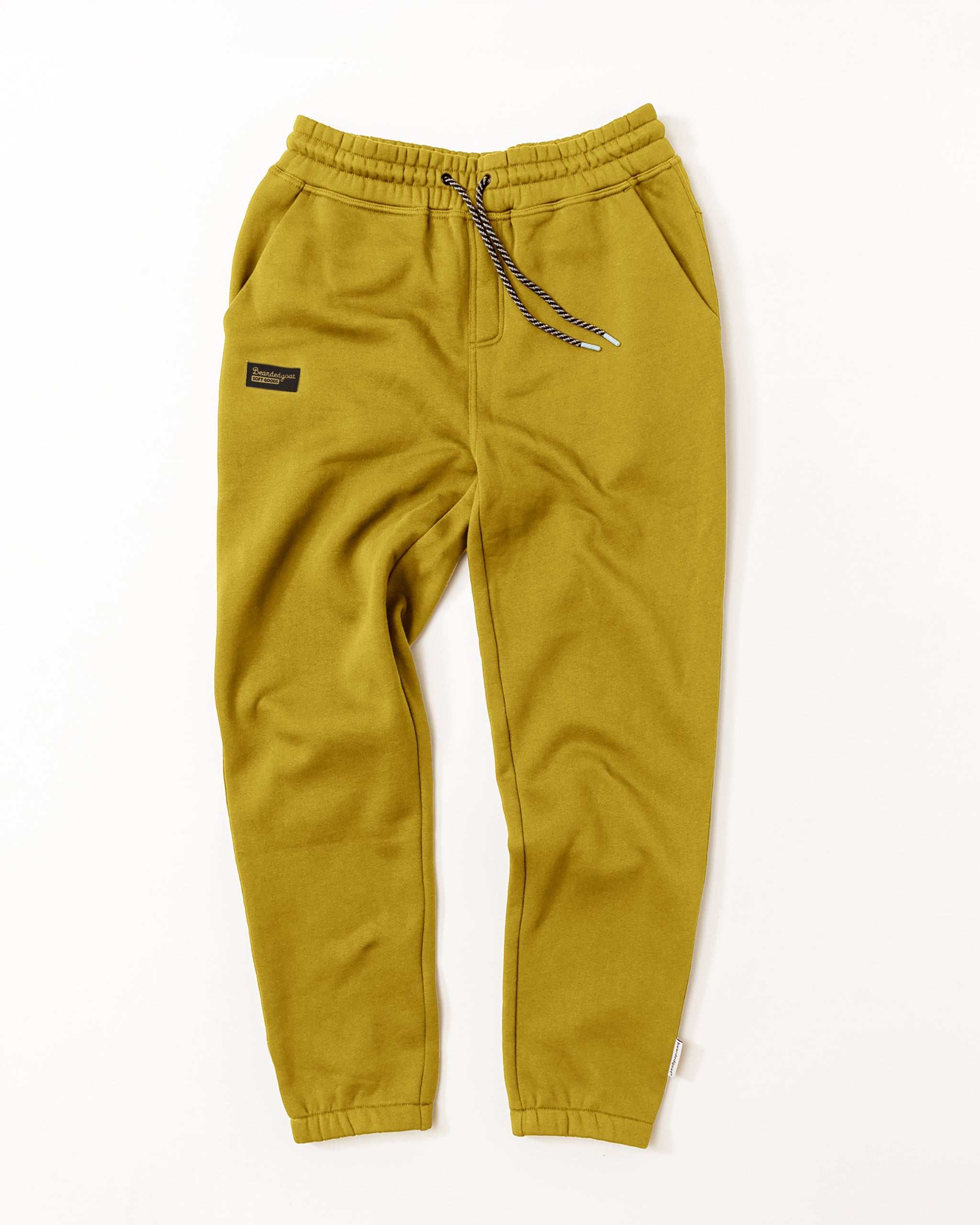 The beardedgoat VOID™ Sweatpant in olive green premium cotton features an elastic waistband, navy and white drawstring, side pockets, and a black patch label on the left thigh, displayed flat on a white background.