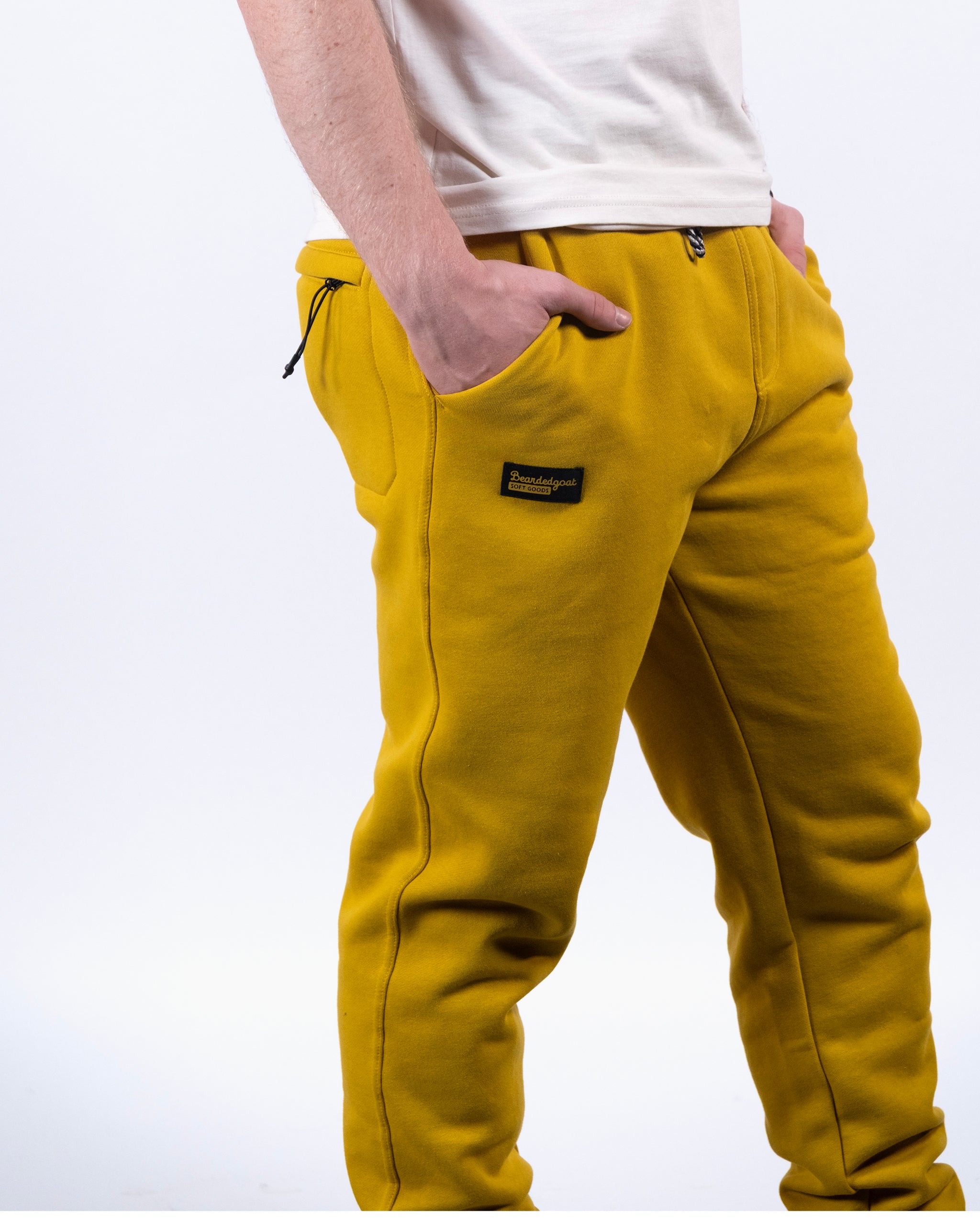 A person wears a white t-shirt and beardedgoat VOID™ Sweatpant in bright yellow, with hands in both pockets, standing against a plain white background.