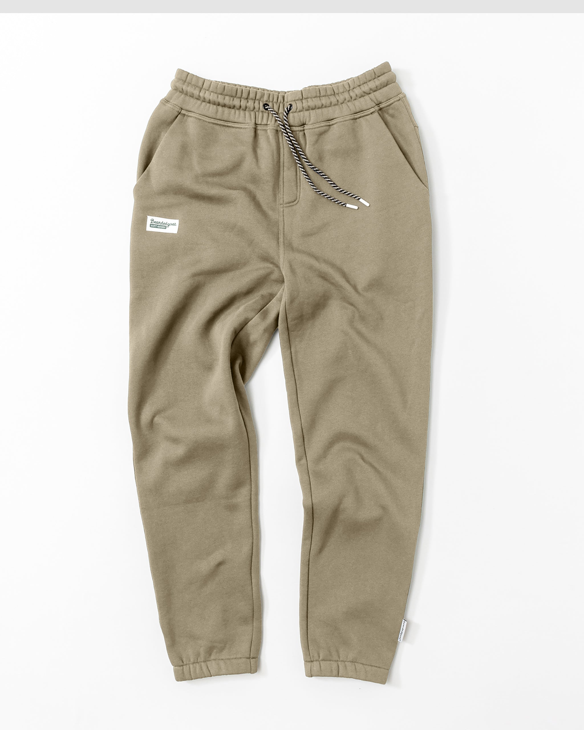 Men’s Void Sweatpants by beardedgoat in olive green with an elastic waistband, drawstring, side pockets, and a small white thigh patch, laid flat on a white background. Durable and stylish joggers.