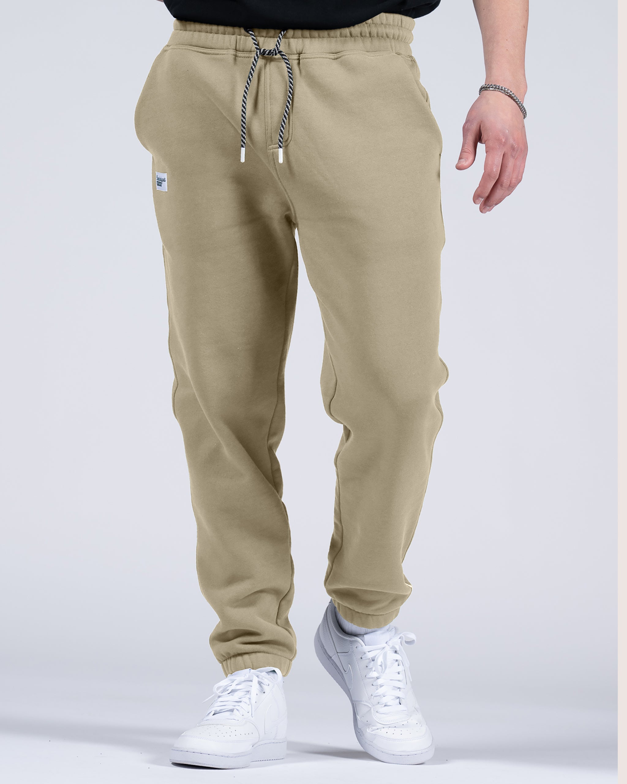 A person models beardedgoat Men's Void Sweatpants, featuring a drawstring waist, paired with white sneakers. Only the lower half of their body is visible against a plain, light background.