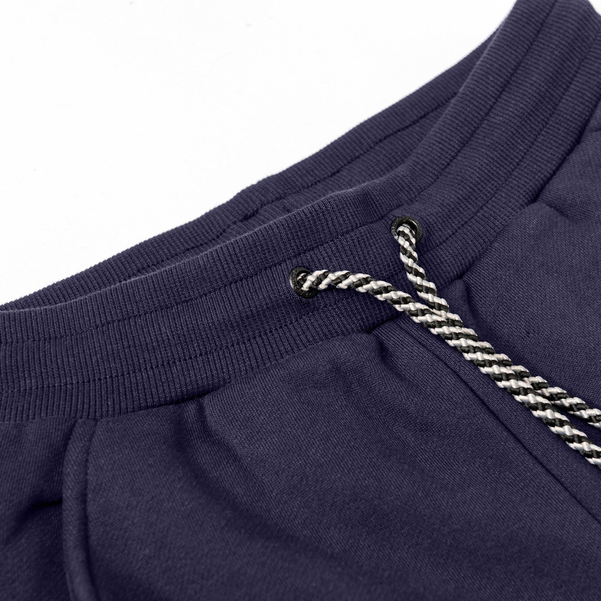 Close-up of the beardedgoat Women’s Overnight Sweatpant in dark blue, made from heavyweight cotton fleece, featuring a black and white braided drawstring threaded through metal eyelets.