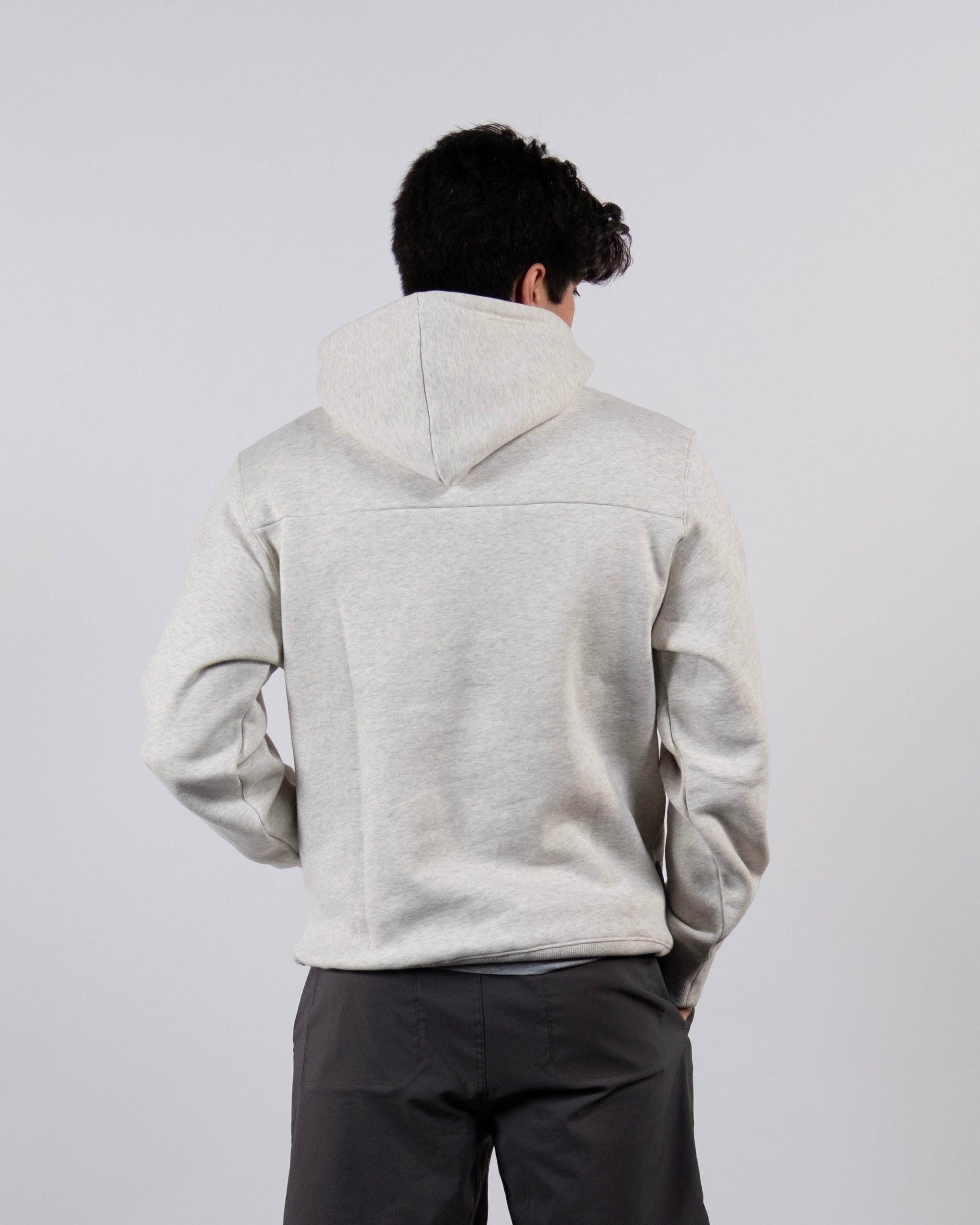A person wearing the beardedgoat The VOID™ Hoodie in light gray and dark gray pants stands with their back to the camera against a plain light background.
