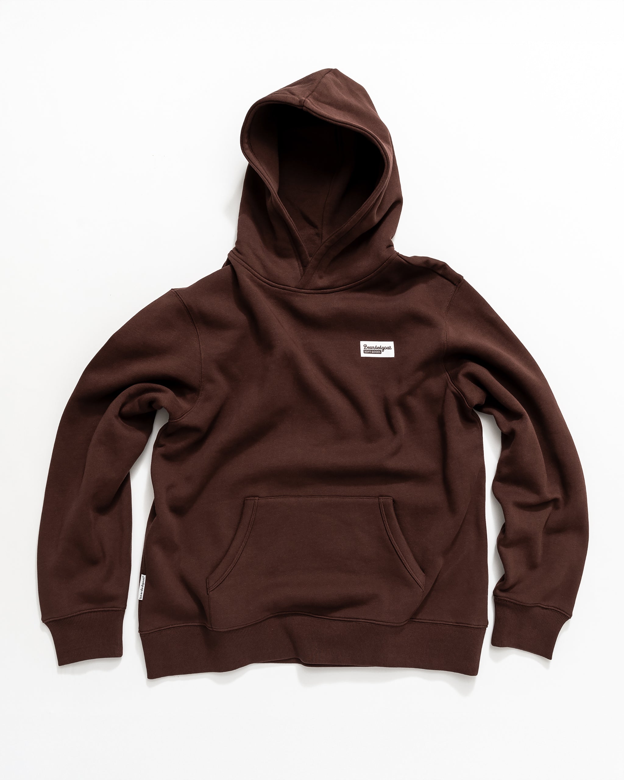 The beardedgoat Men's Void Hoodie in brown heavyweight cotton features a front kangaroo pocket and a small white rectangular label on the left chest, shown laid flat on a white background.