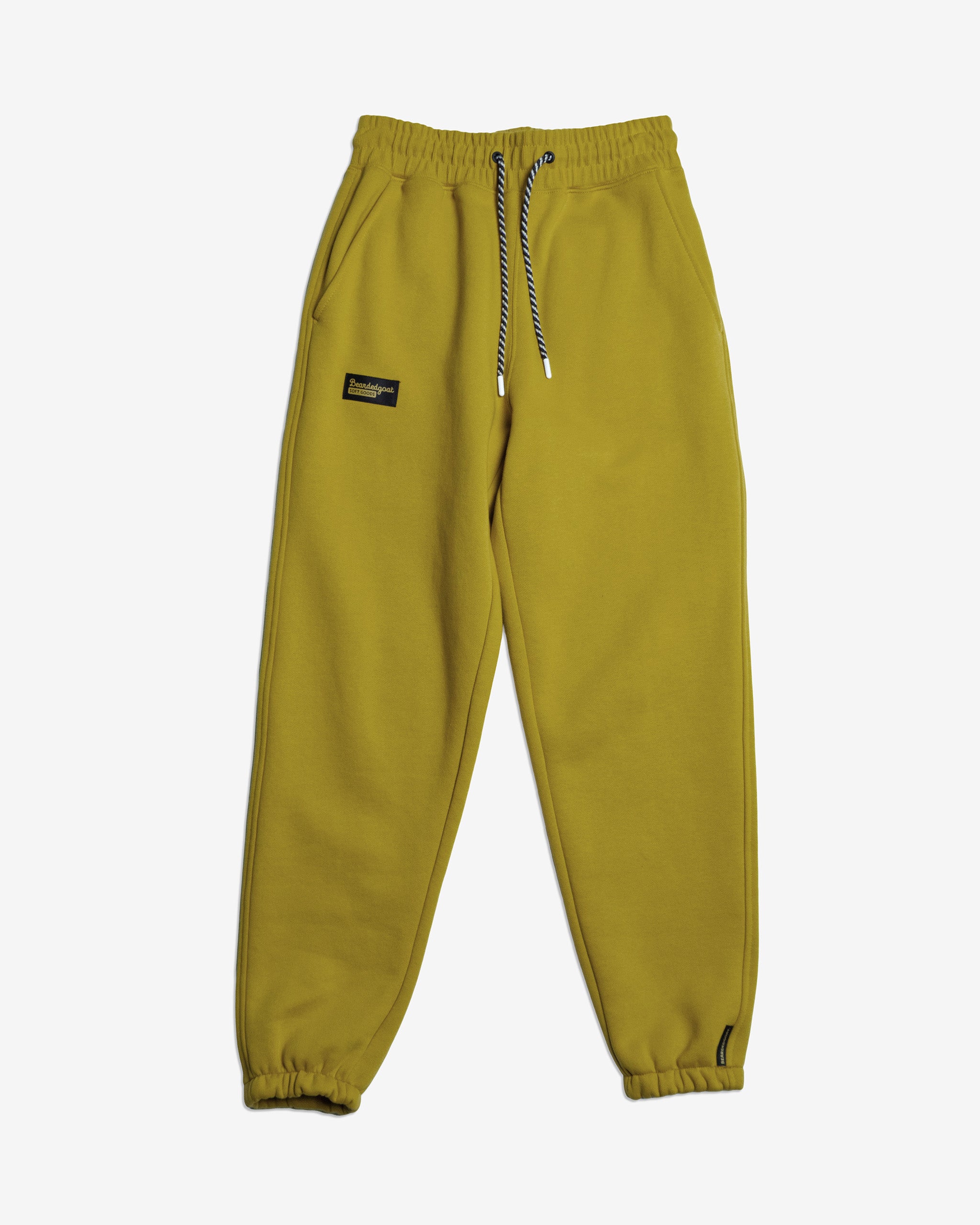 The NEW — Overnight™ Classic Jogger by BEARDEDGOAT features yellow-green heavyweight cotton fleece, an elastic high-rise waistband with black and white drawstring, elastic cuffs, side pockets, and a black patch label on the left thigh.
