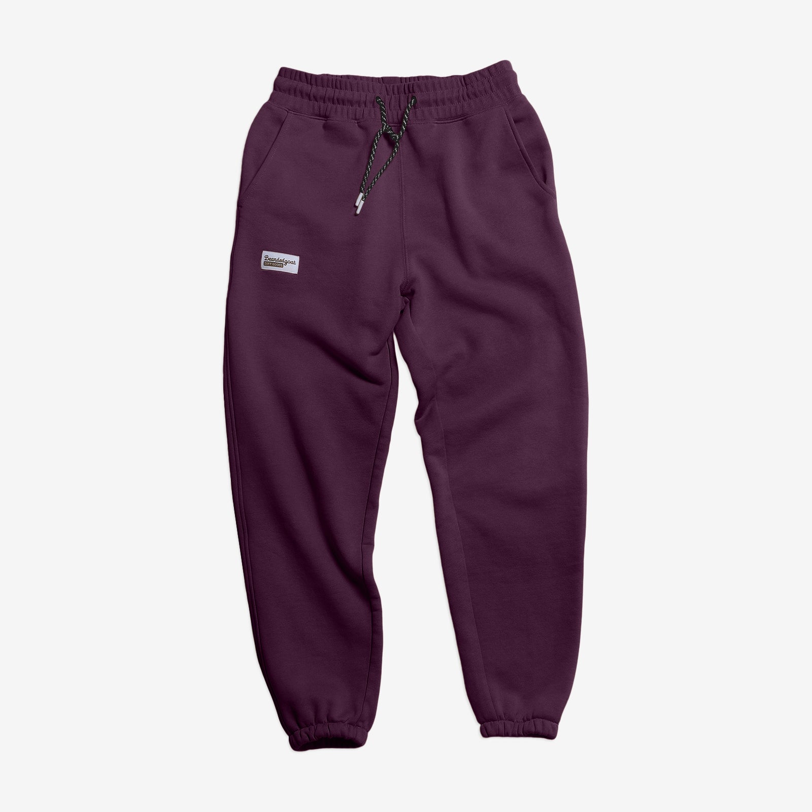 The NEW — Overnight™ Classic Jogger by BEARDEDGOAT is a dark purple sweatpant with a high-rise waistband, black drawstring, side pockets, elastic cuffs, and a small rectangular label on the left thigh. Made from heavyweight cotton fleece.