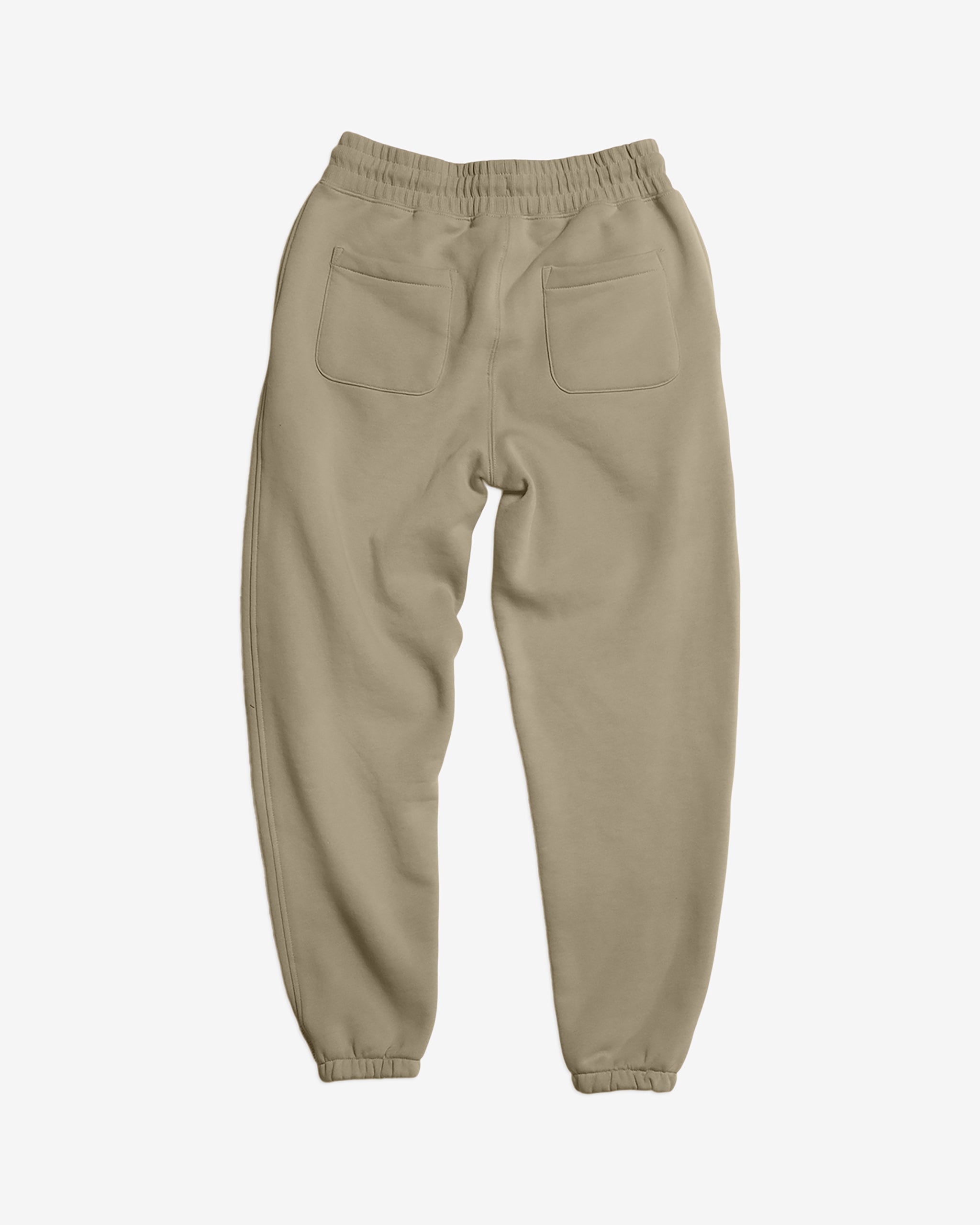 The BEARDEDGOAT Women’s Overnight™ Classic Jogger in beige is shown from the back, featuring a high-rise waistband, two rear patch pockets, and elastic ankle cuffs—crafted from heavyweight cotton fleece and laid flat on a white background.