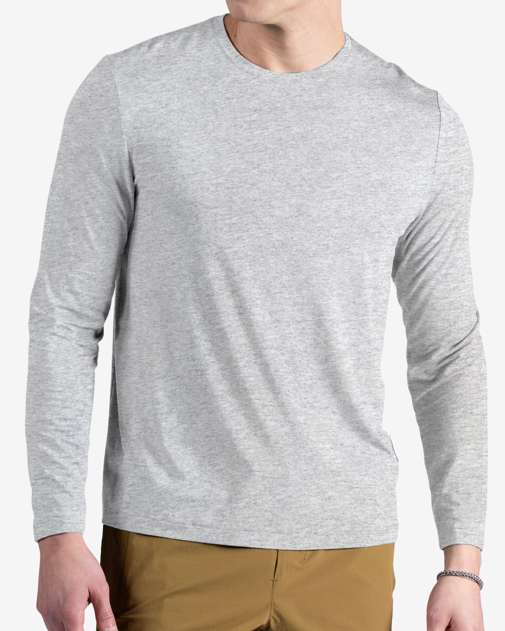 A man in a light grey BEARDEDGOAT Men’s EverZen™ Long Sleeve bamboo blend crew neck shirt and light brown pants stands against a plain white background, with his face partially out of frame.