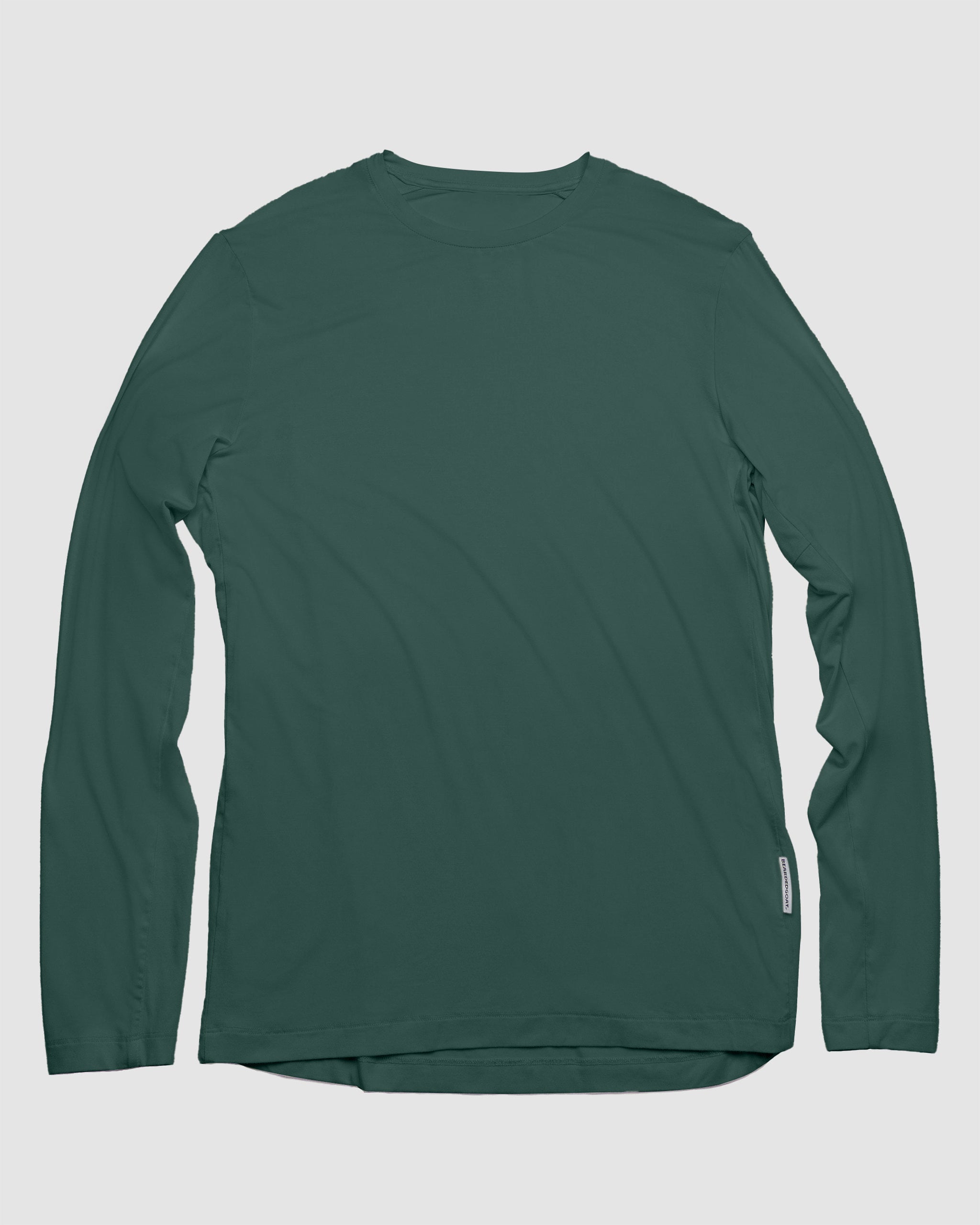 The BEARDEDGOAT Men’s EverZen™ Long Sleeve in Cypress, in a soft bamboo blend, is shown laid flat on a white background. It features a crew neck, long sleeves, and a small rectangular tag on the lower right side seam.