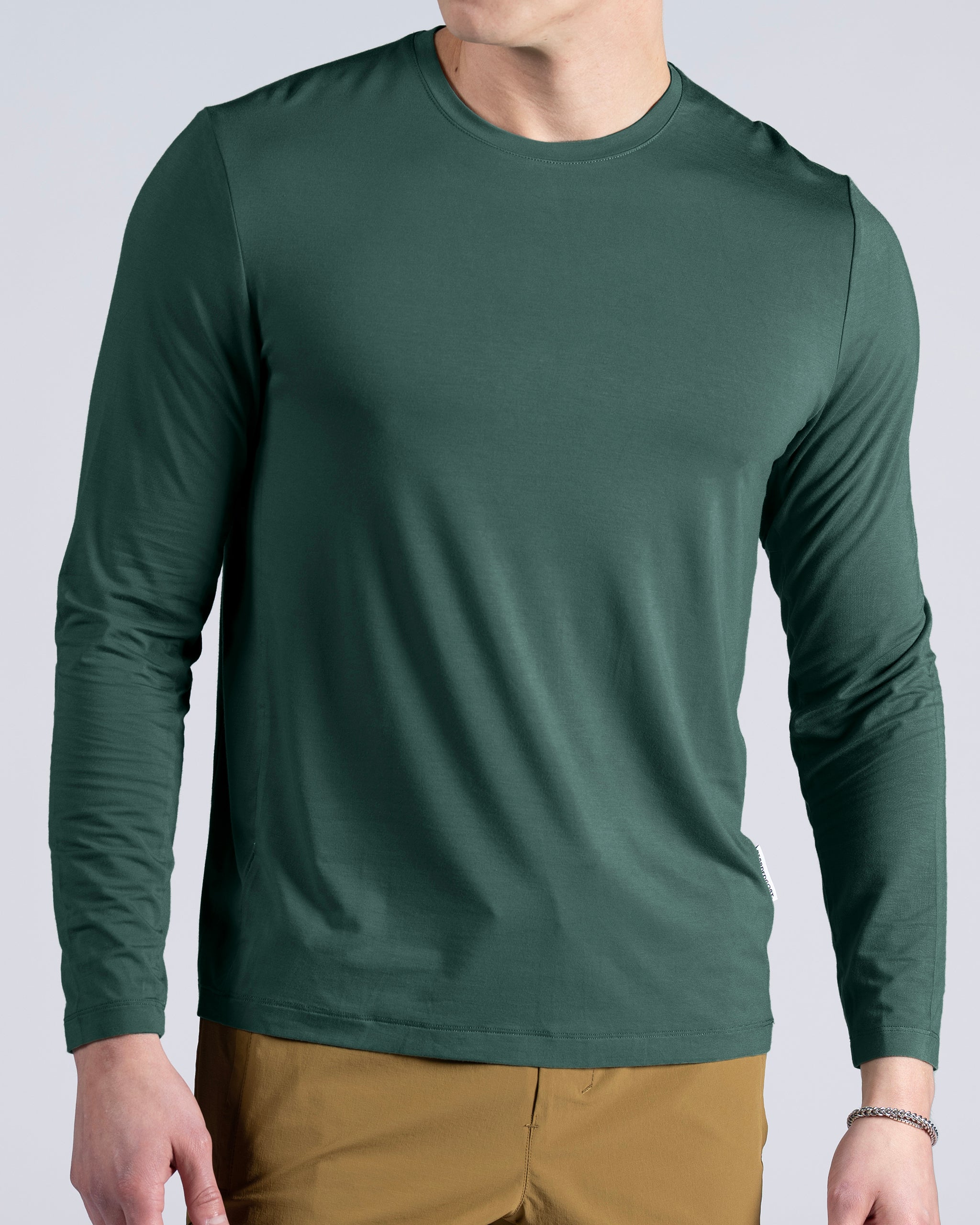 A person wearing a BEARDEDGOAT Men’s EverZen™ Long Sleeve in dark green and light brown pants, shown from the shoulders down against a plain background.