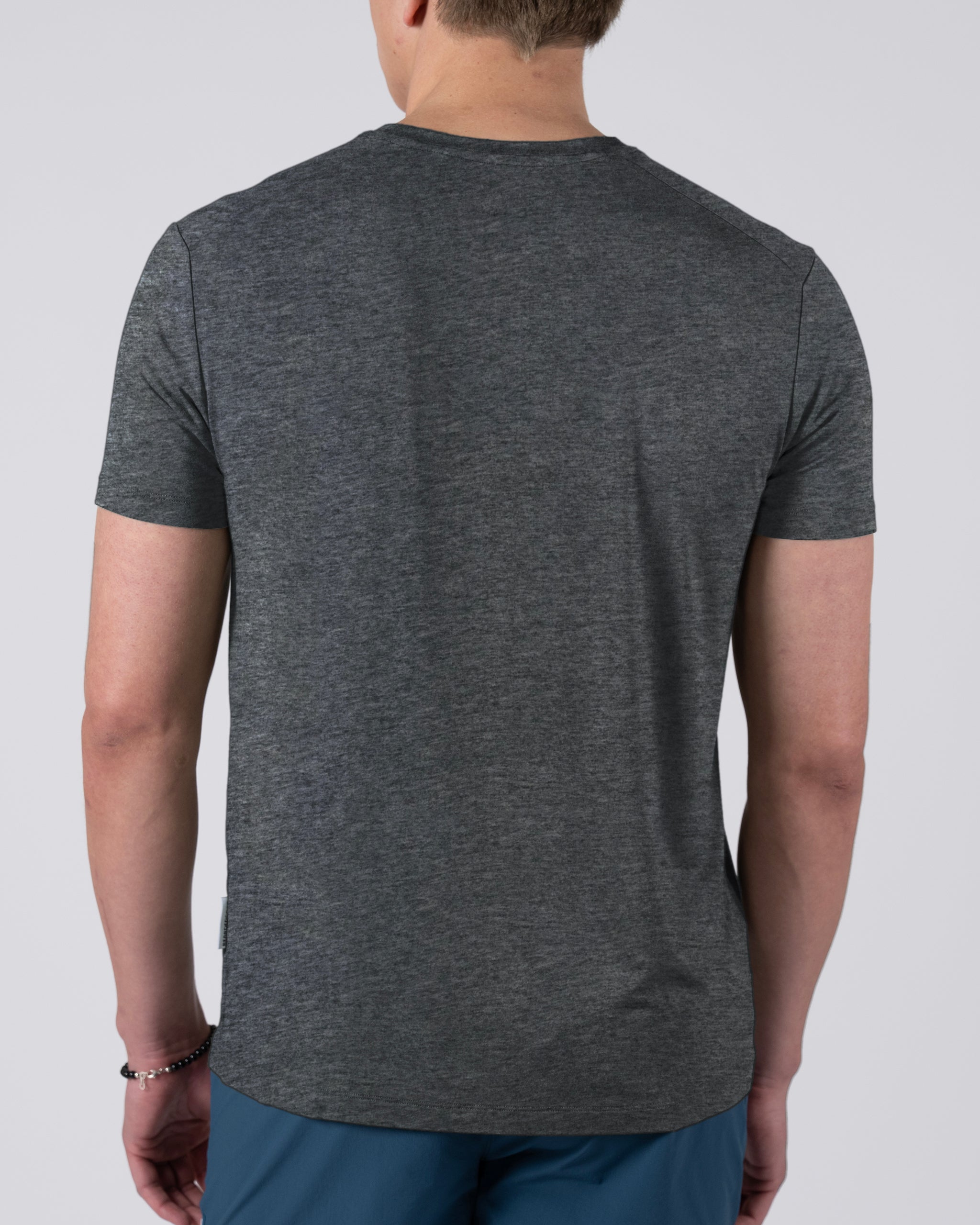 A person is shown from the back against a plain light background, wearing a dark gray BEARDEDGOAT Men’s EverZen™ Short Sleeve crew neck t-shirt and blue pants.