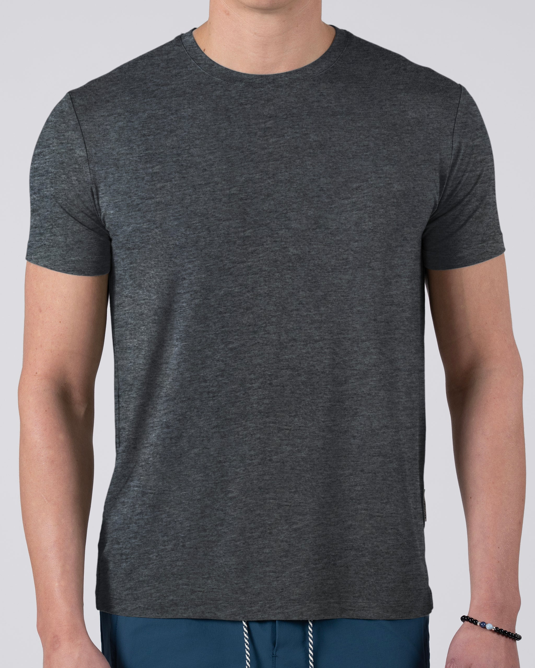 A person in a BEARDEDGOAT Men’s EverZen™ Short Sleeve, dark gray, and blue pants stands against a light gray background with their face not visible.
