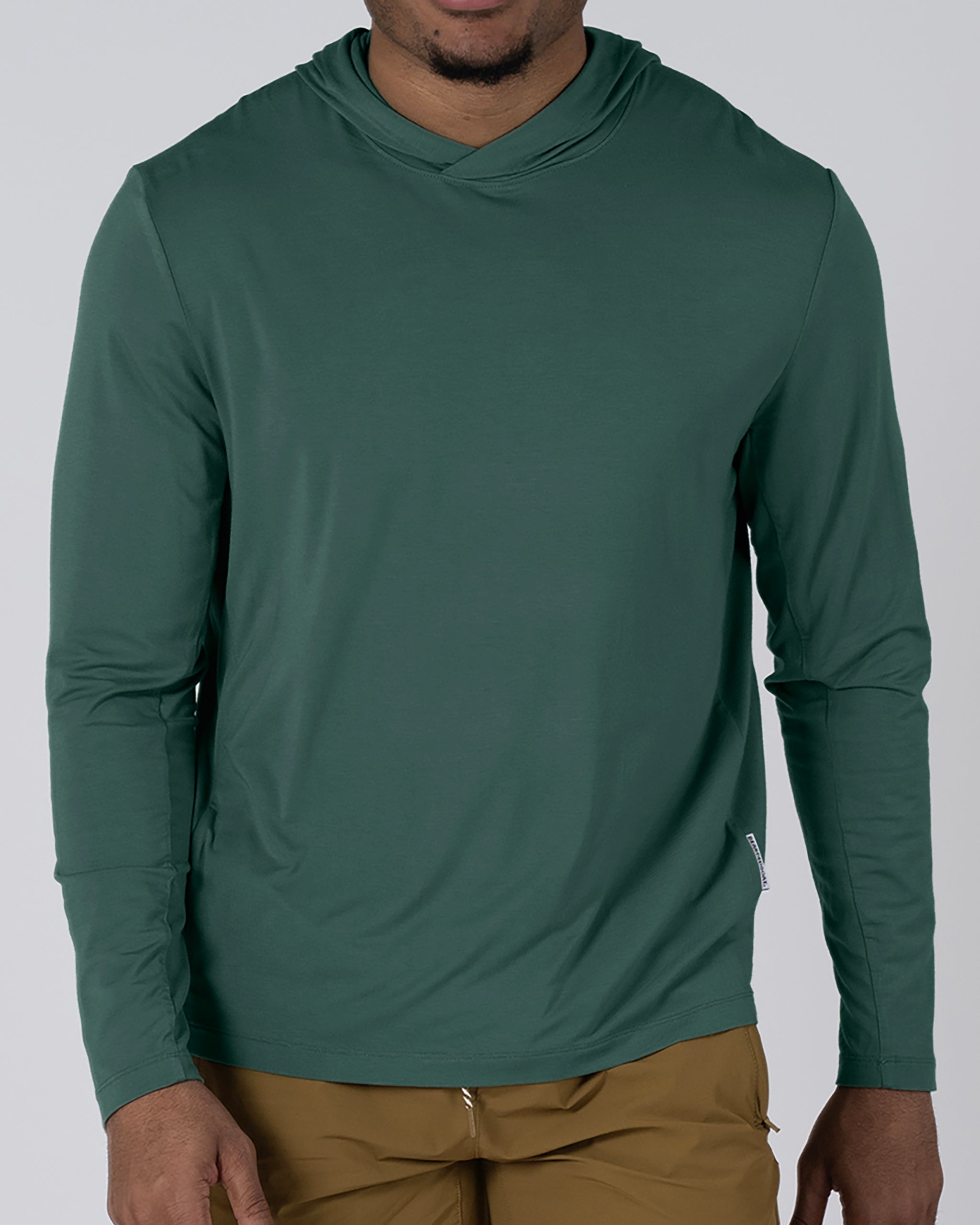 A person wears the BEARDEDGOAT Men’s EverZen™ Hoodie in forest green and light brown pants, shown from the waist up against a plain background. The cropped frame draws focus to this sustainable bamboo hoodie.