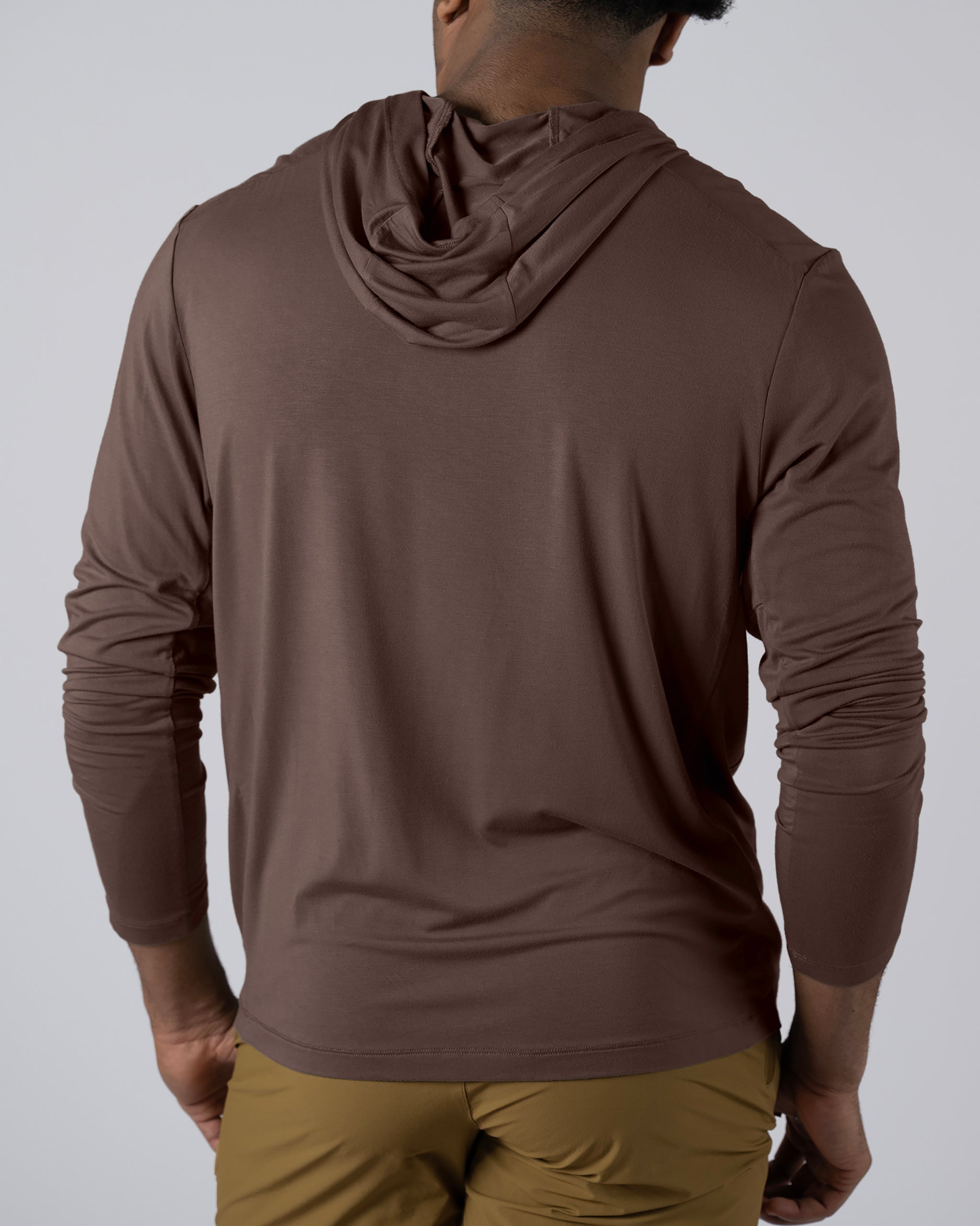 A person is shown from the back wearing a brown BEARDEDGOAT Men’s EverZen™ Hoodie and light brown pants, standing against a plain light gray background.