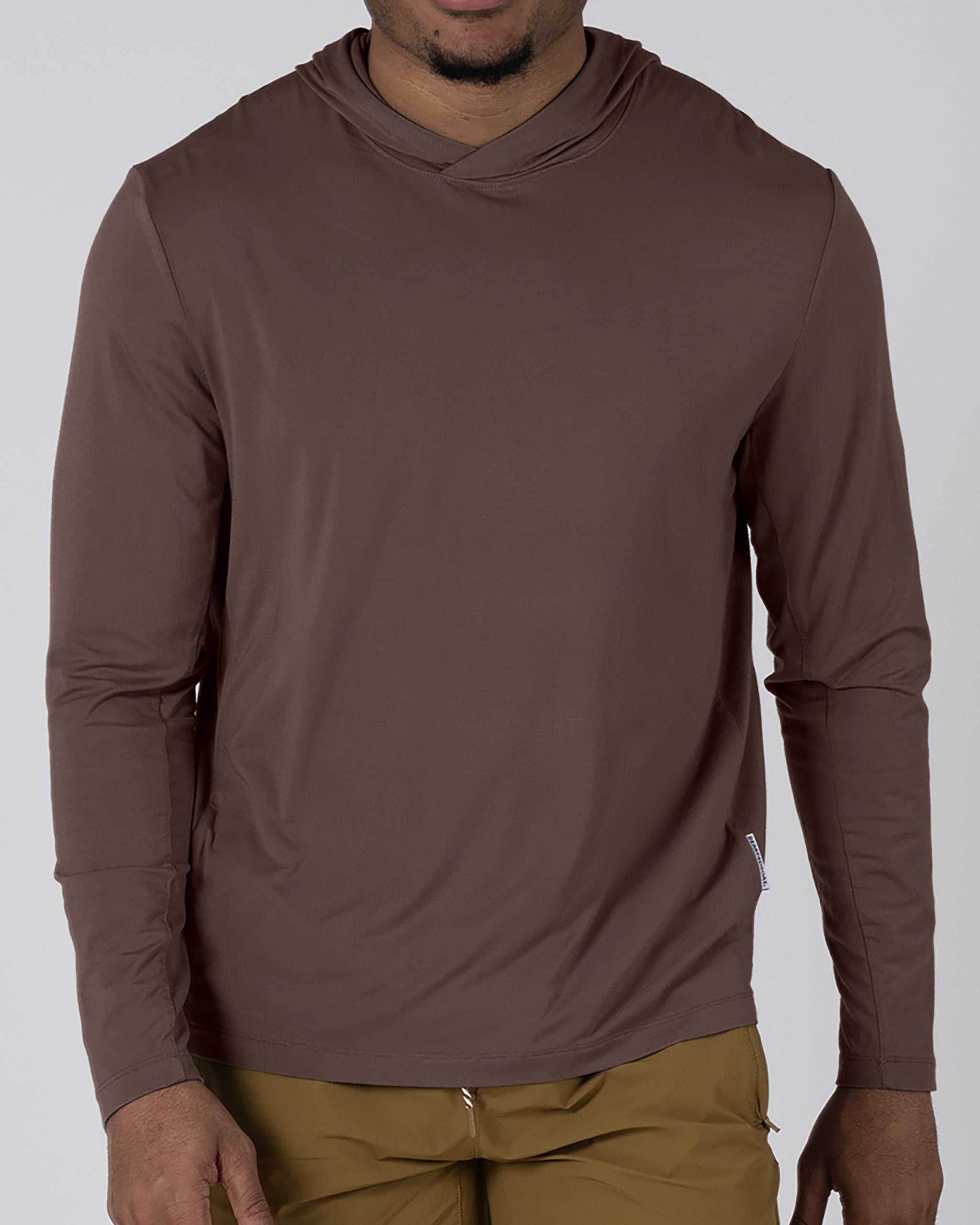 A man stands against a light gray background wearing the BEARDEDGOAT Men’s EverZen™ Hoodie in brown and mustard-colored pants, with his head partially out of the frame.
