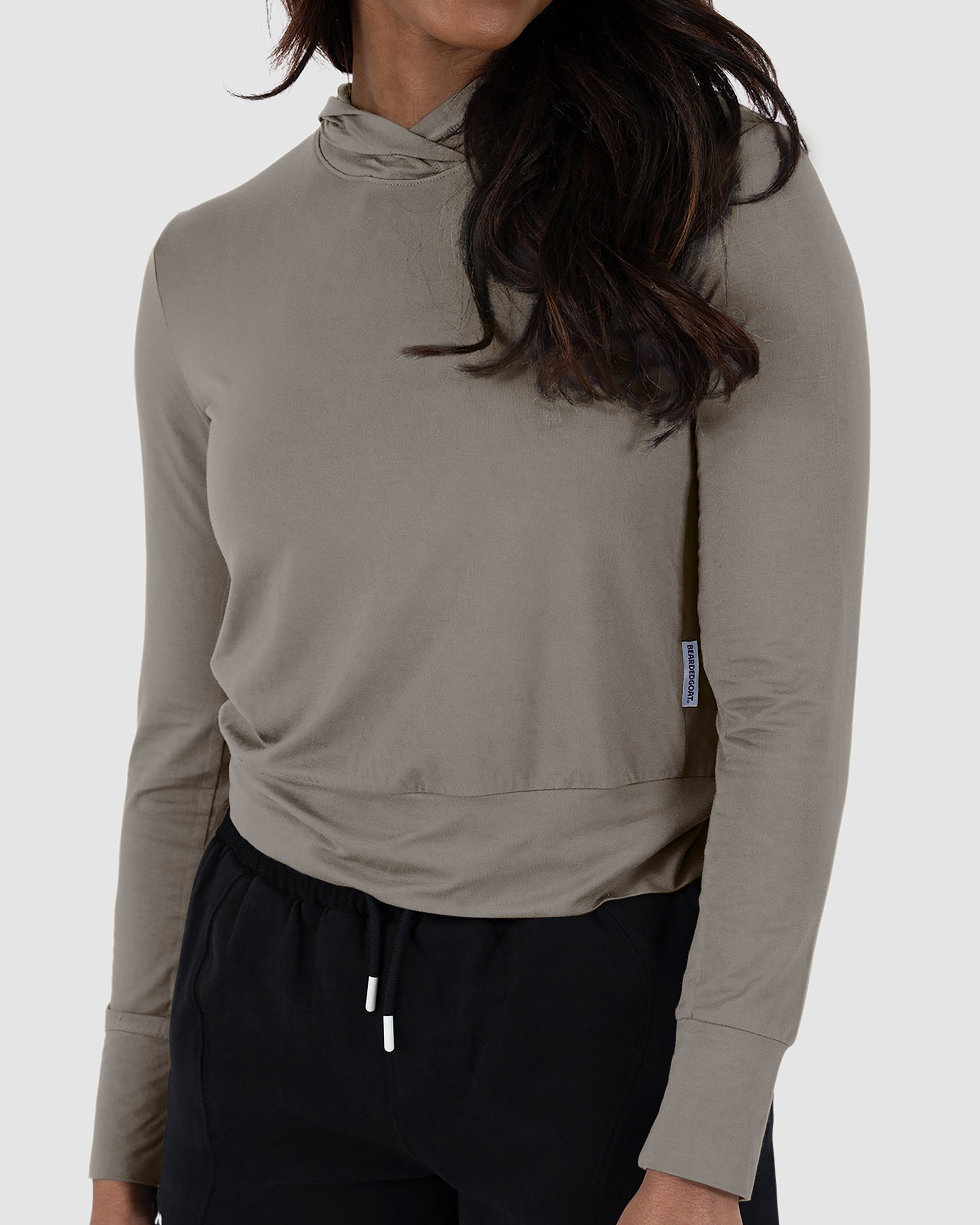 A woman wearing the BEARDEDGOAT Women’s EverZen™ Bamboo Hoodie in Terra Sienna with black pants, one hand relaxed at her side, shown from shoulders to hips against a plain background.