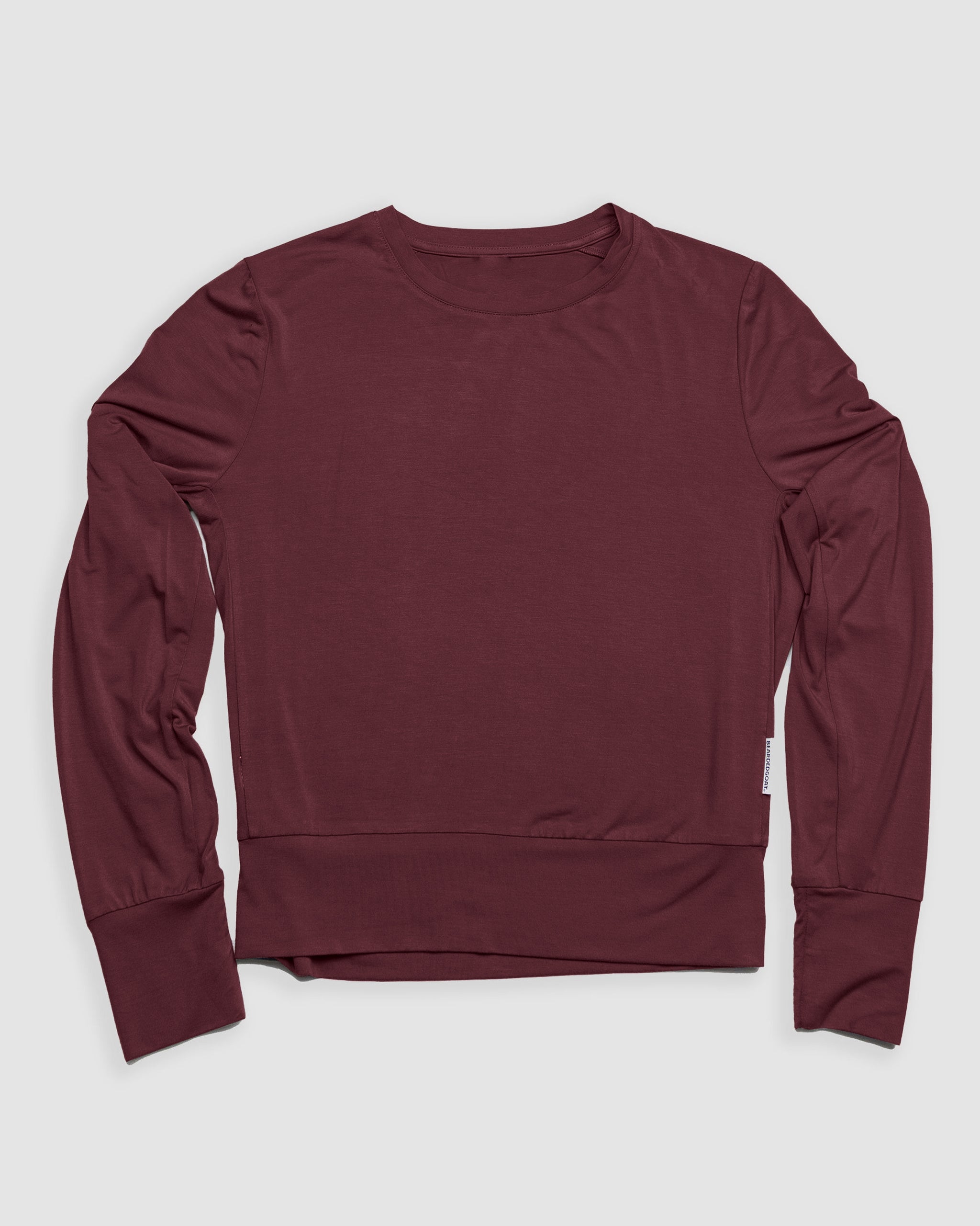 The BEARDEDGOAT Women’s EverZen™ Bamboo Long Sleeve, an eco-friendly, solid burgundy crew neck top, is laid flat on a light gray background. Made from a sustainable bamboo blend, it has a simple design with no visible patterns or logos.