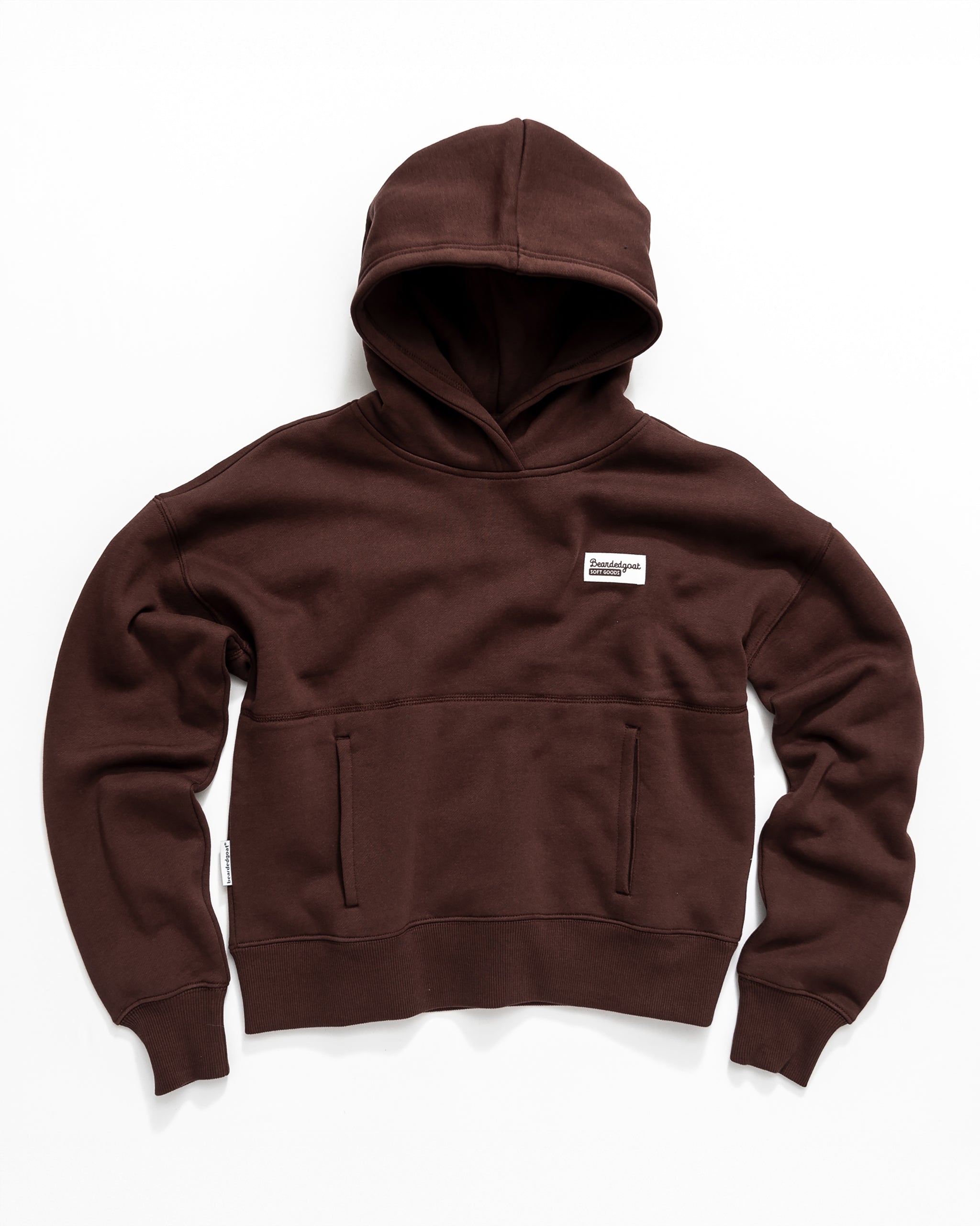 The beardedgoat Women's Overnight Hoodie is a brown heavyweight cotton fleece with a front pocket and a small white rectangular chest label, shown laid flat on a white background.