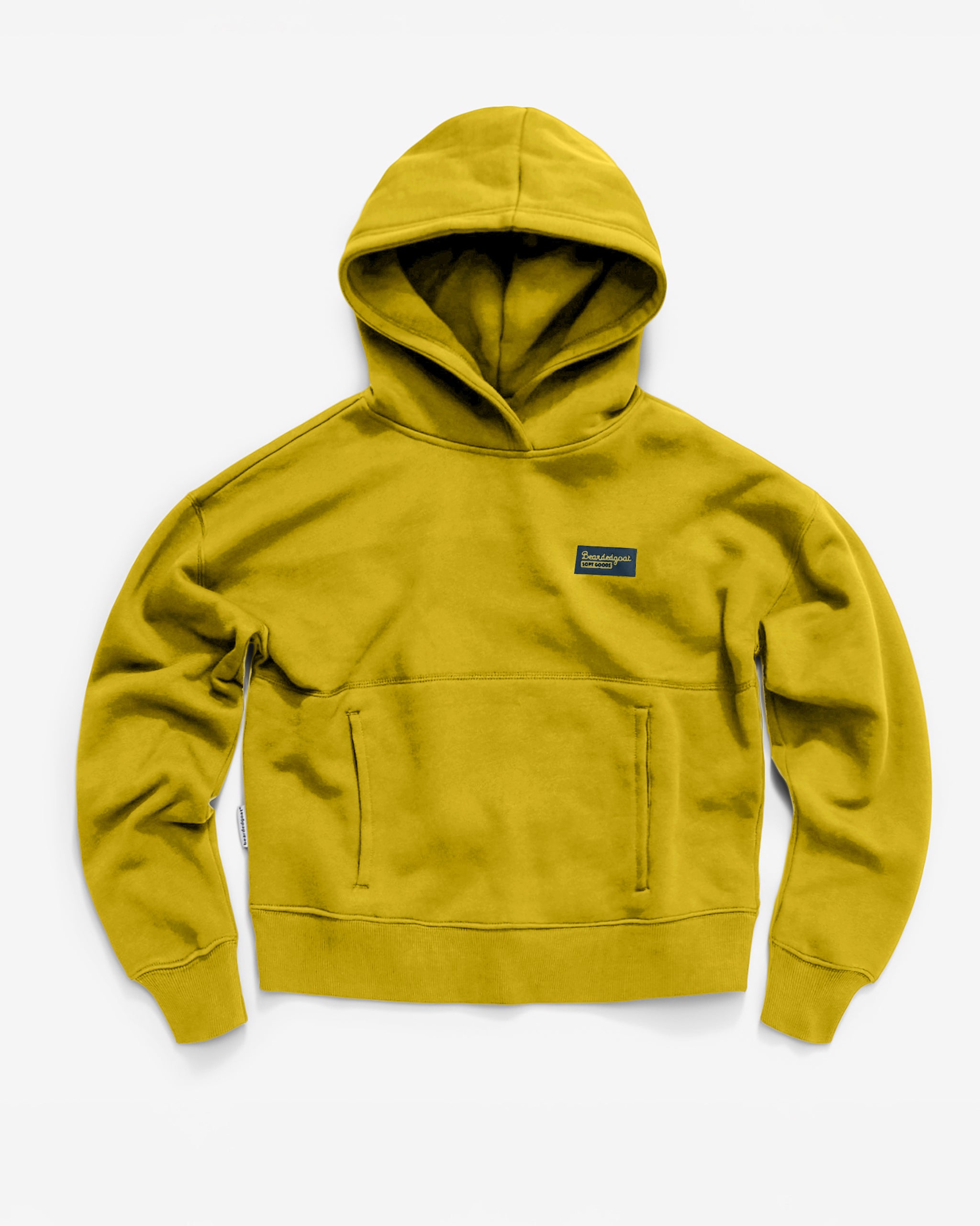 The Women's Overnight™ Hoodie by beardedgoat, shown on a white background, comes in mustard yellow with heavyweight cotton fleece, a front pocket, and a small black rectangular label on the left chest.