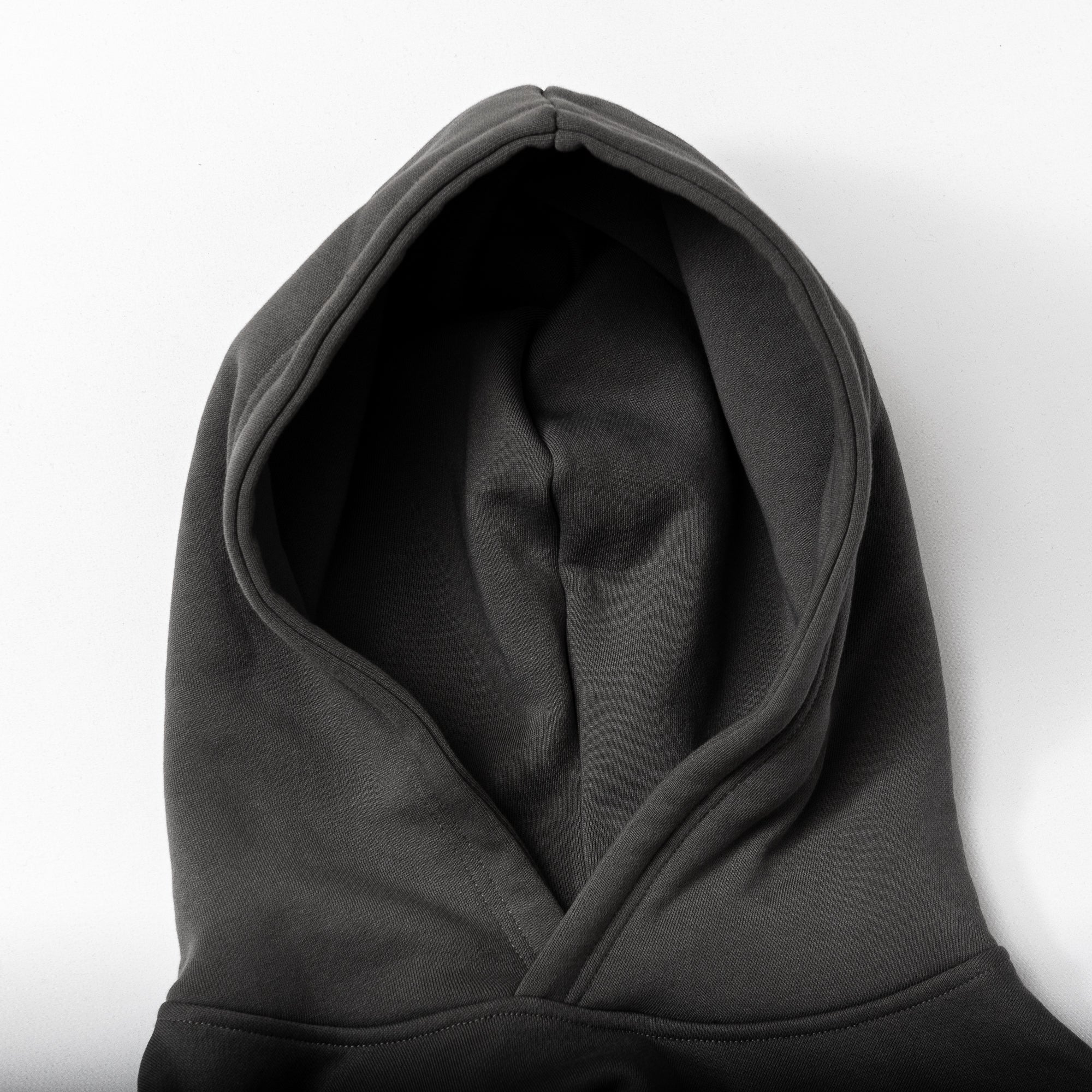 A top view of The VOID™ Hoodie by beardedgoat, shown flat with the hood up on a white surface. Crafted from heavyweight cotton fleece, its fabric looks soft and subtly textured.