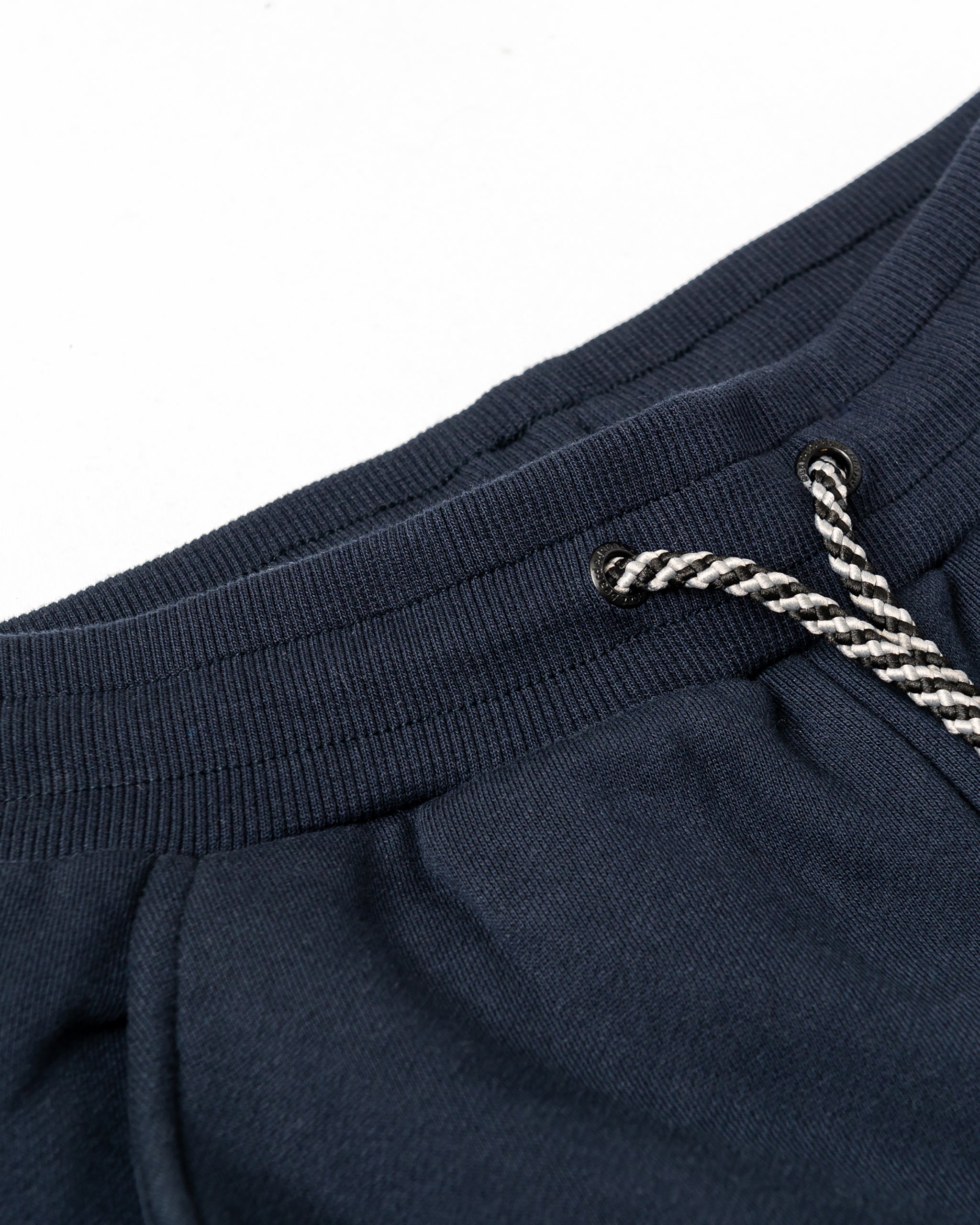Close-up of the beardedgoat Women’s Overnight Sweatpant’s ribbed waistband, showcasing a black-and-white braided drawstring with metal eyelets, crafted from heavyweight cotton fleece for cozy comfort.
