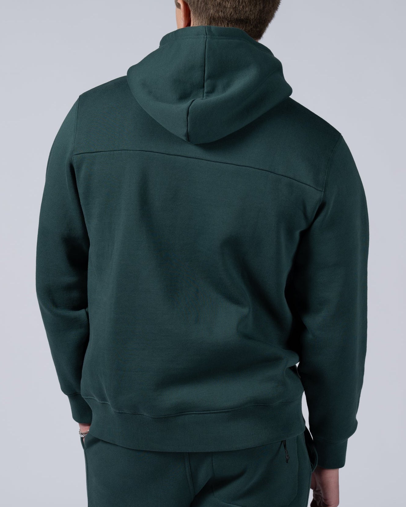 A person wearing a beardedgoat Mens Void Hoodie and matching sweatpants stands facing away from the camera against a plain light gray background.