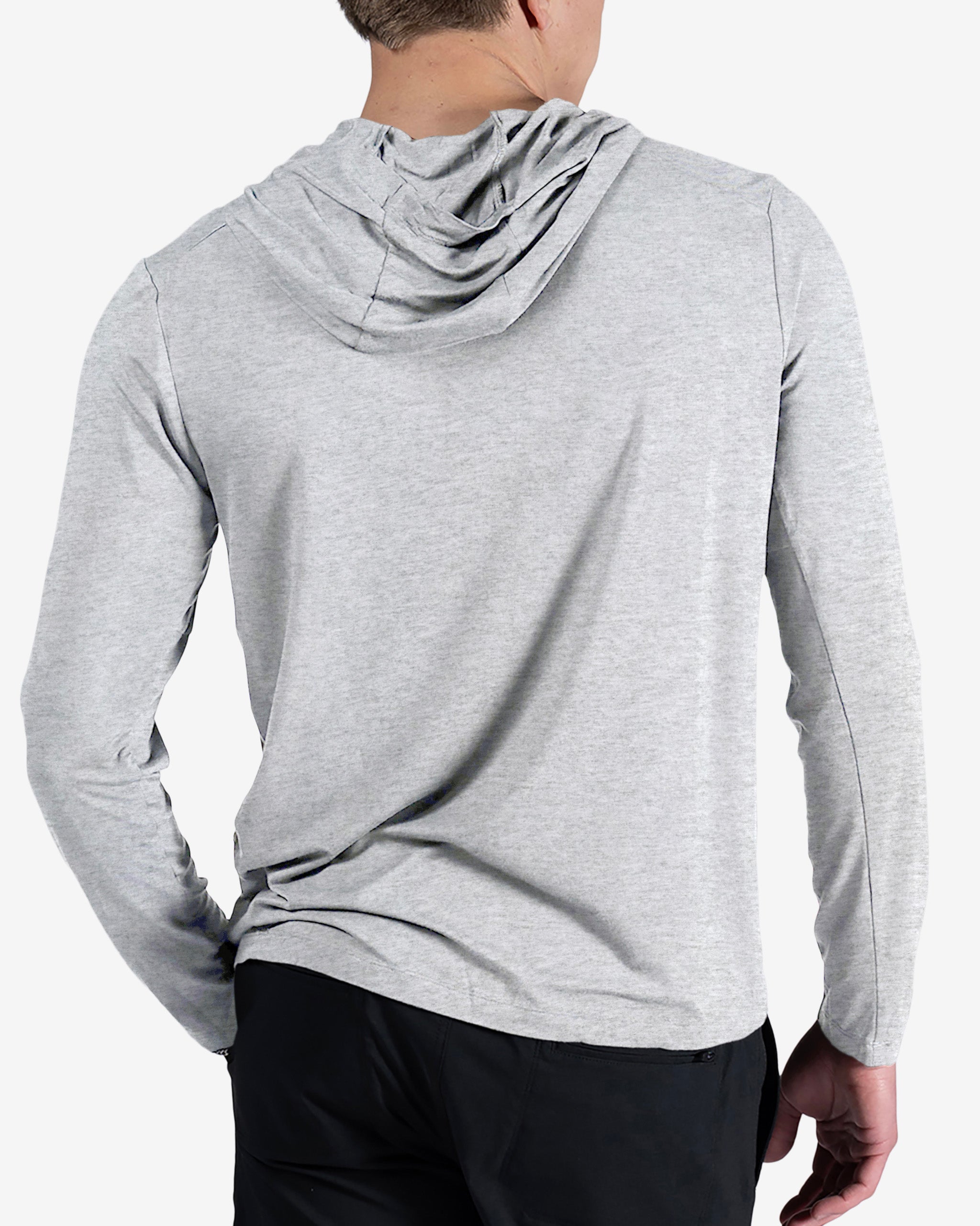 A man stands with his back to the camera, left hand on his hip, wearing the BEARDEDGOAT Men’s EverZen™ Hoodie in light gray and black pants, highlighting modern sustainable style.