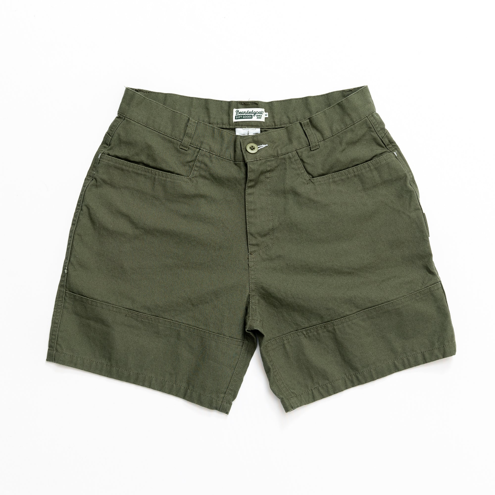 The beardedgoat Mens Foundry Short in olive green, made from rugged cotton canvas with front pockets, button and zip closure, and inner waistband label—an everyday essential shown on a white background.
