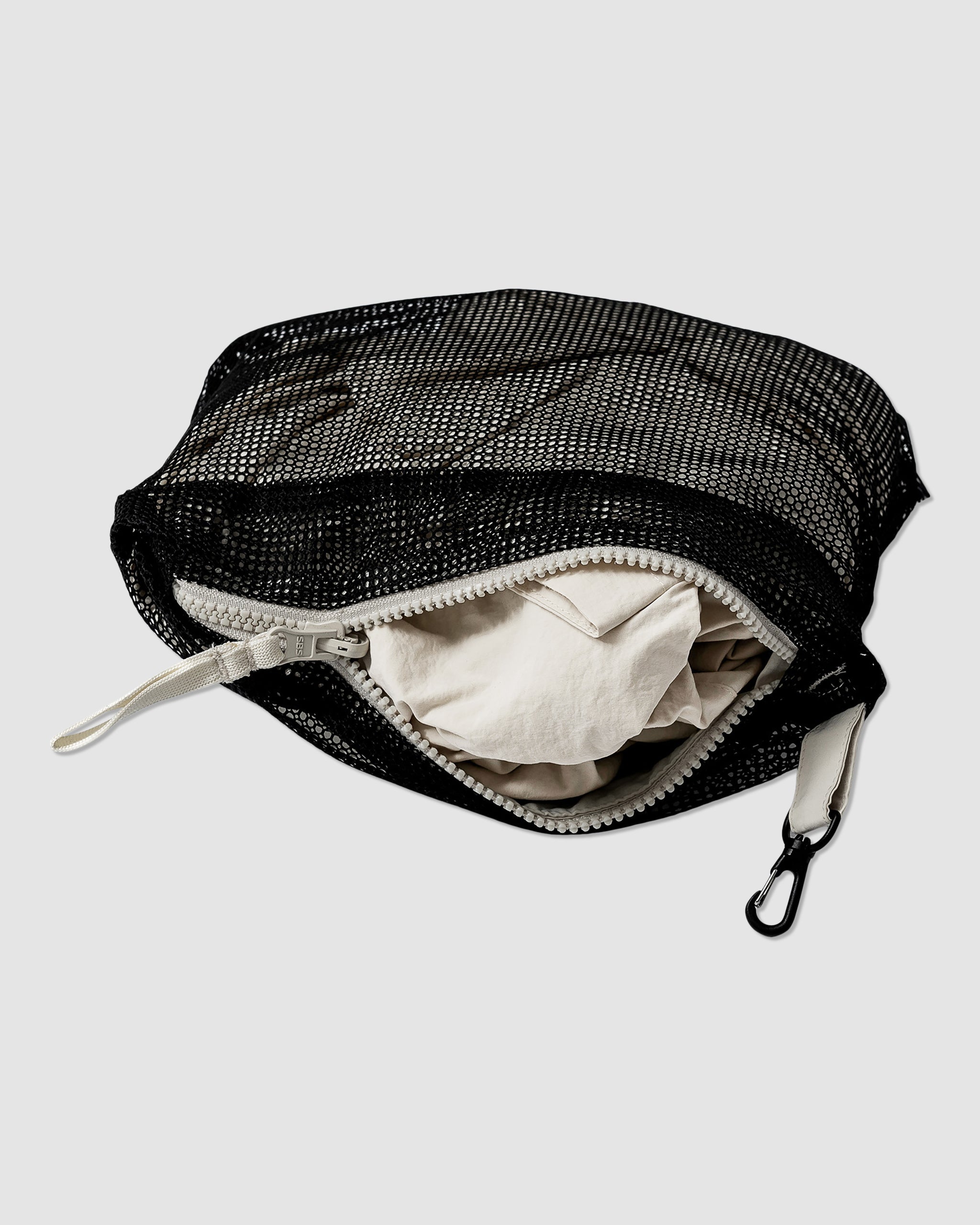 A black mesh, water-resistant zippered pouch with a white zipper, partially open to reveal a folded BEARDEDGOAT Womens Deluge Pullover inside. The pouch features a small black hook on one end.