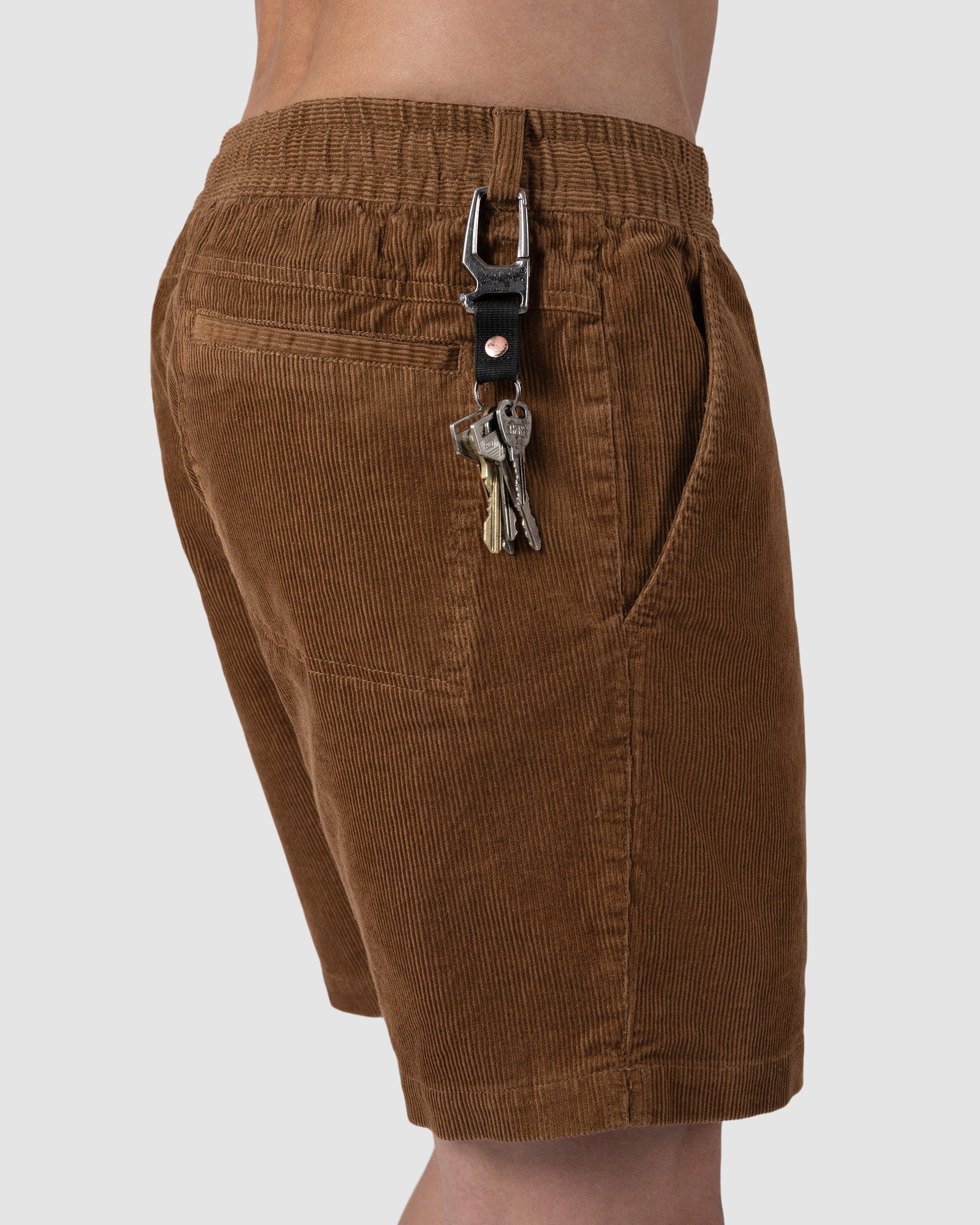 A person sports BEARDEDGOAT Mens Cord Short in brown with vintage flair, showing off the textured side pocket and a black leather keychain with metal keys on the belt loop.
