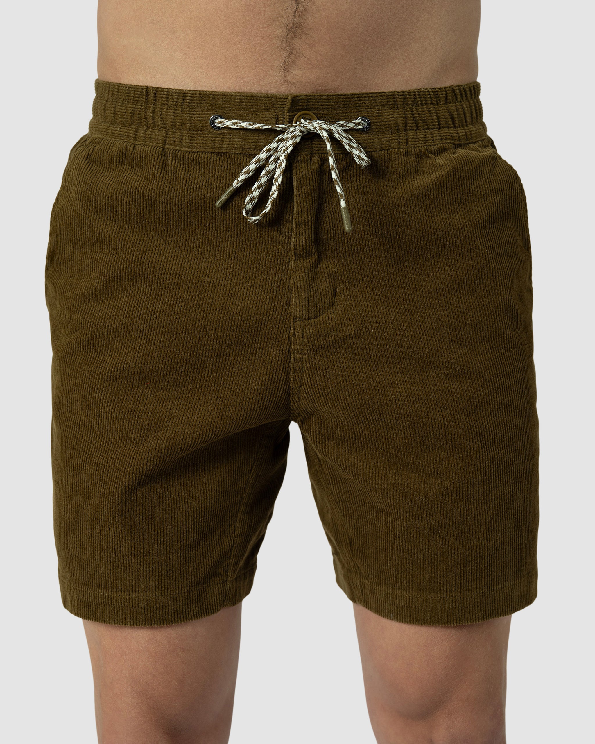 A person wearing BEARDEDGOAT Mens Cord Short, featuring an elastic waistband and a white and black drawstring, stands against a light gray background.