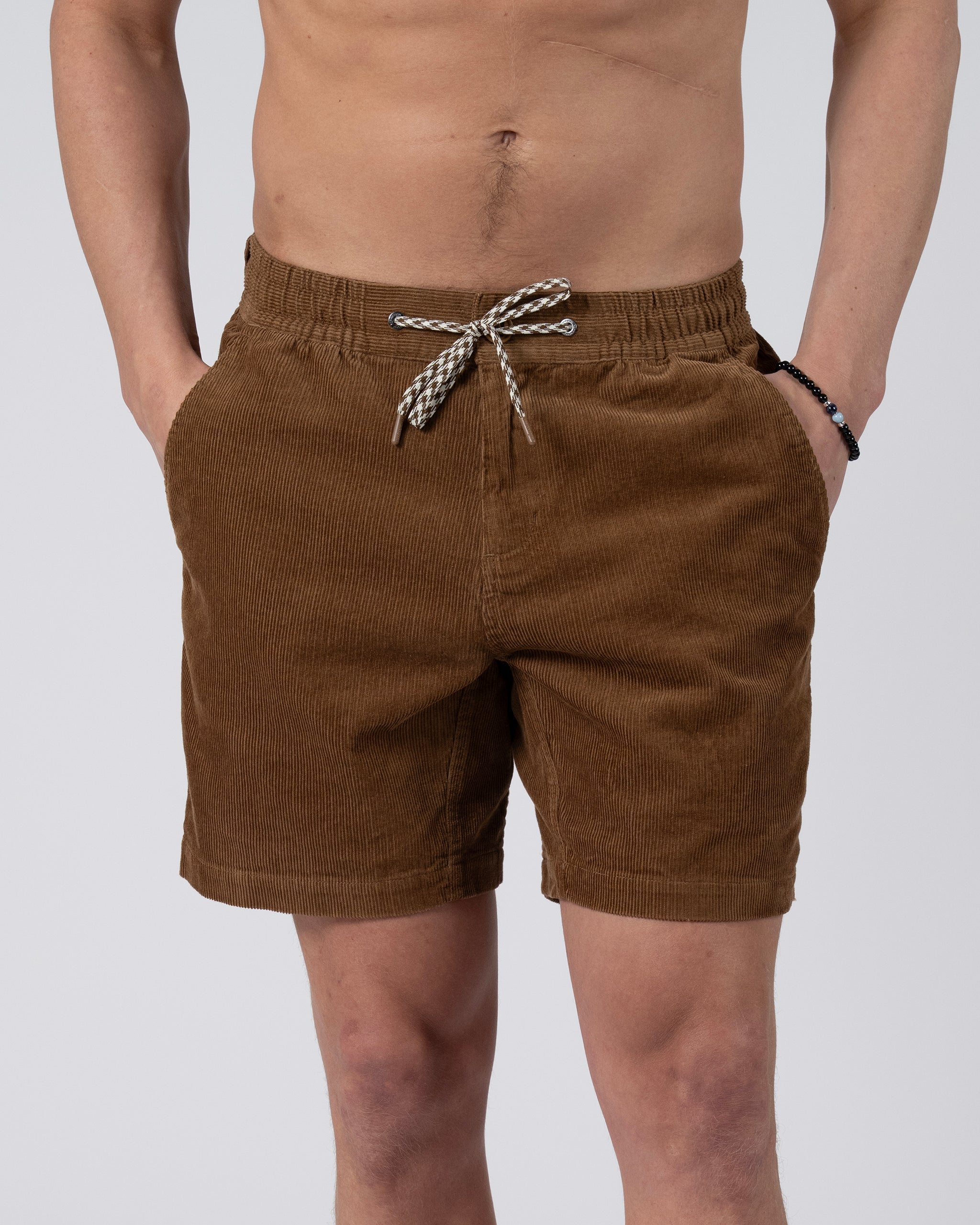 A person models the BEARDEDGOAT Men's Cord Short—vintage corduroy with elastic waistband and black-and-white drawstring, hands in pockets against a plain light gray backdrop, highlighting its everyday versatility.