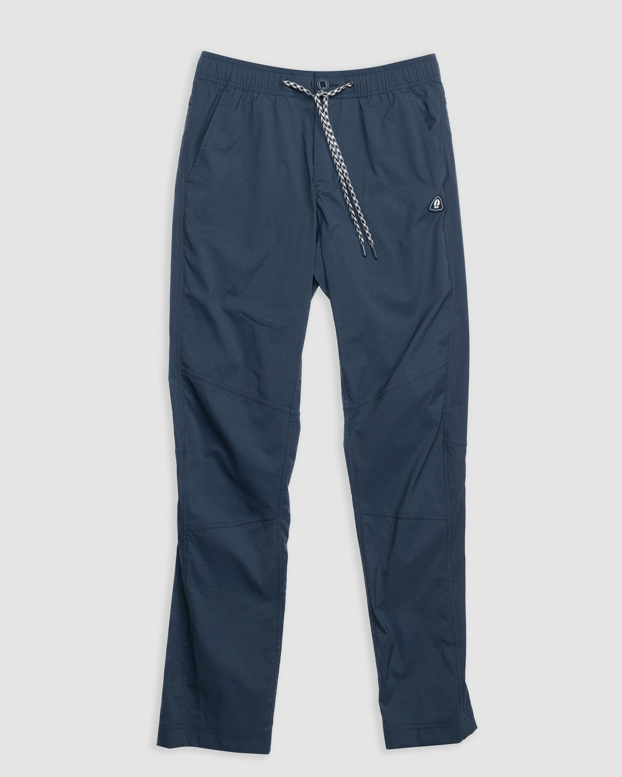 The BEARDEDGOAT NEW-—ROVER™ Pant is a navy 4-season pant with a white and black braided drawstring, elastic waistband, side pockets, and logo patch on the left hip, made from durable performance stretch nylon. Shown laid flat on a light background.
