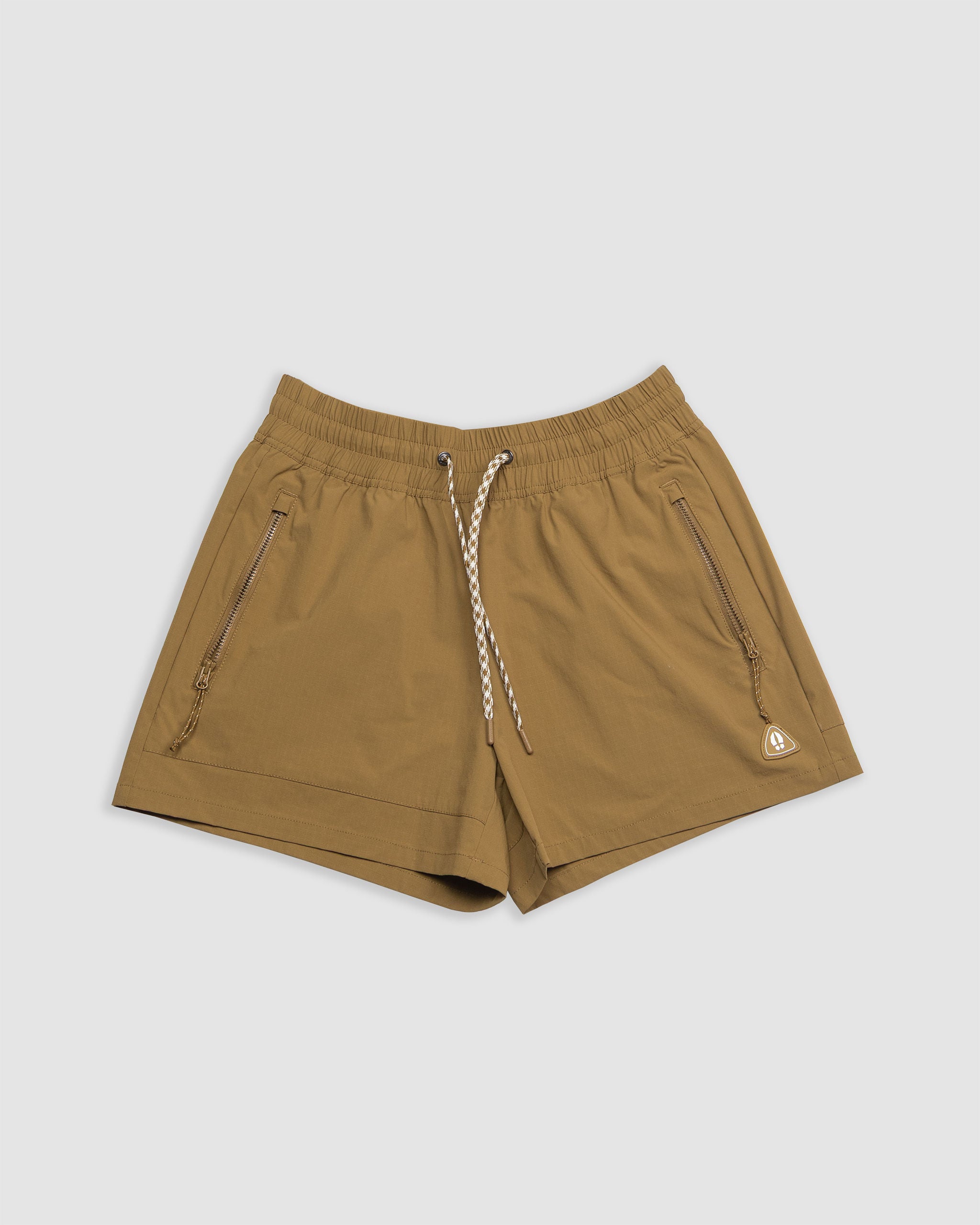 The BEARDEDGOAT Women's Alpina Short in Burnt Amber features a high waist, elastic waistband with white drawstring, zippered pockets, and a small triangular logo on the lower left, shown against a plain light background.