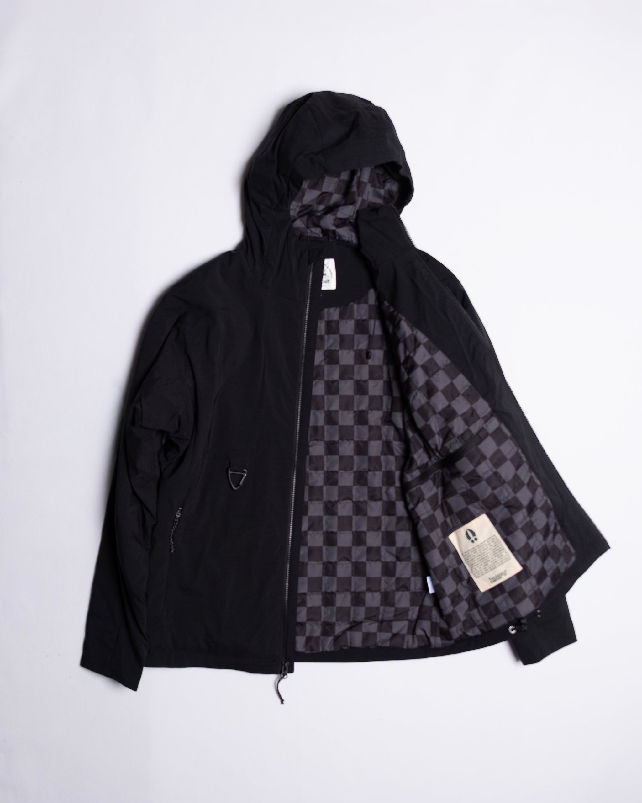 The beardedgoat NEW — OSLO Rover™ Performance All-Season Jacket in black is laid flat, unzipped to display its gray and black checkered lining with interior labels, showcased on a plain white background.