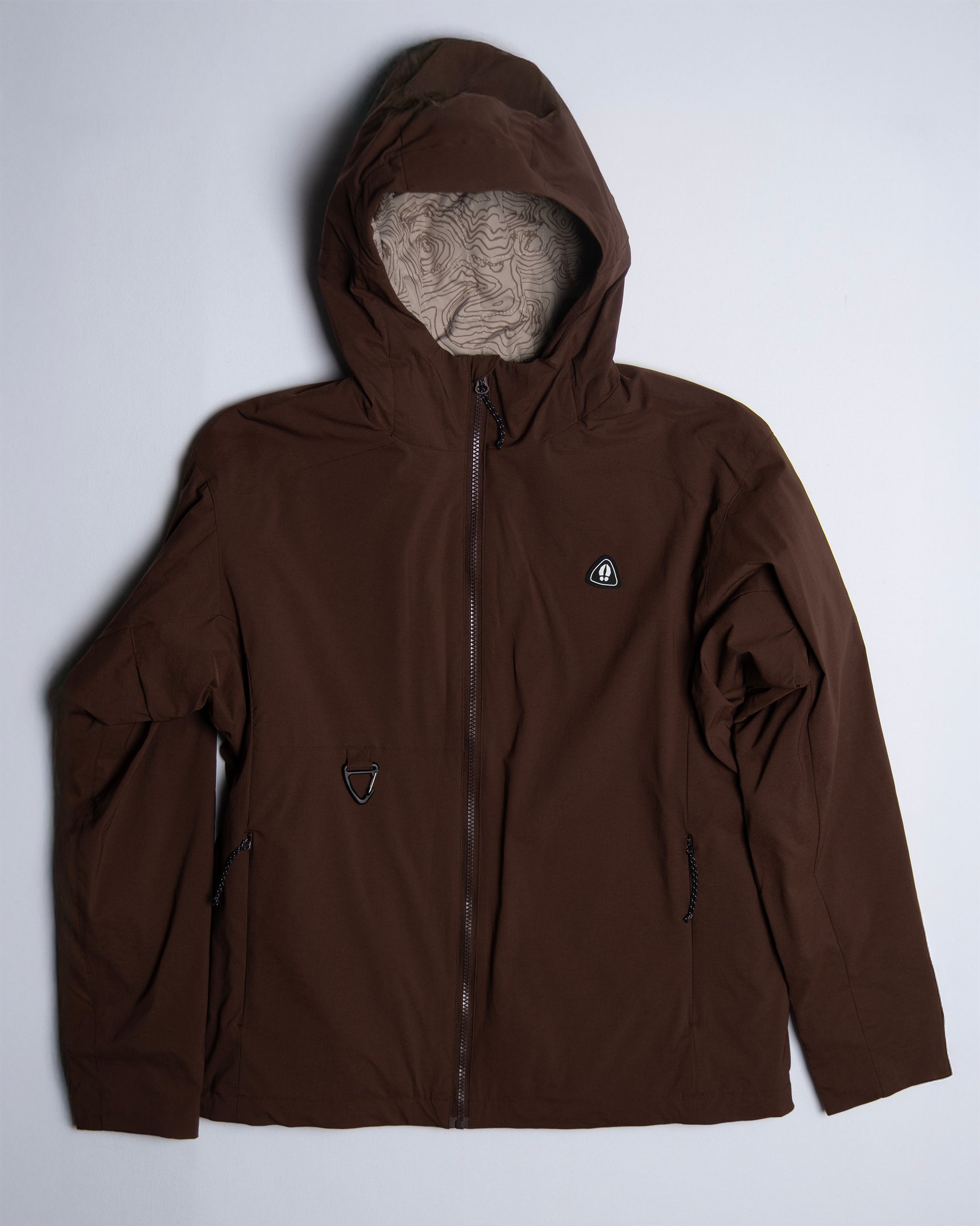 The beardedgoat NEW — OSLO Rover™ Performance All-Season Jacket features a brown zip-up front, two zippered side pockets, a small chest logo, and a patterned hood lining—ideal performance outerwear for any season.