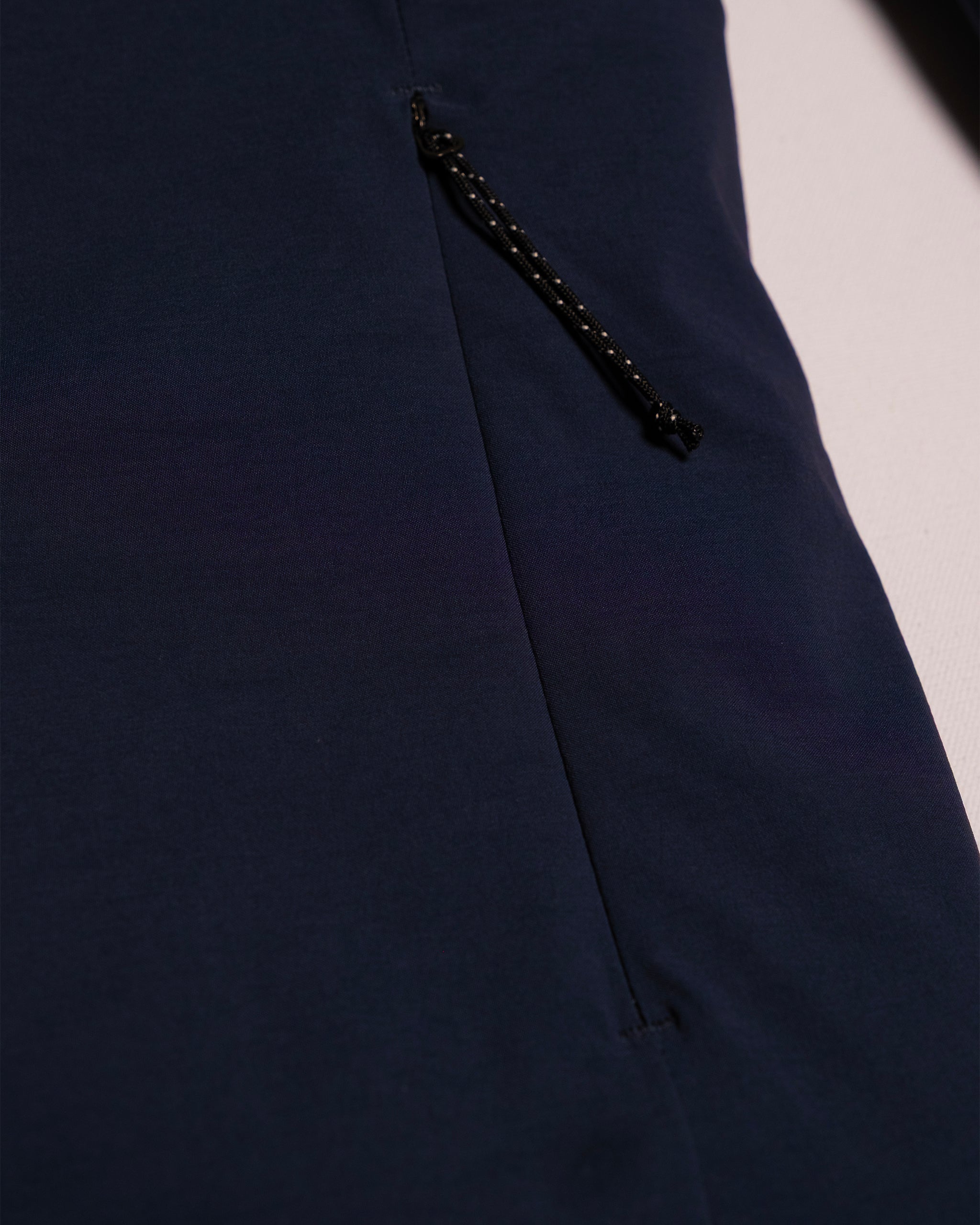 Close-up of the beardedgoat NEW — OSLO Rover™ Performance All-Season Jacket in navy blue, featuring a black zippered pocket with a textured pull, laid on a light surface.
