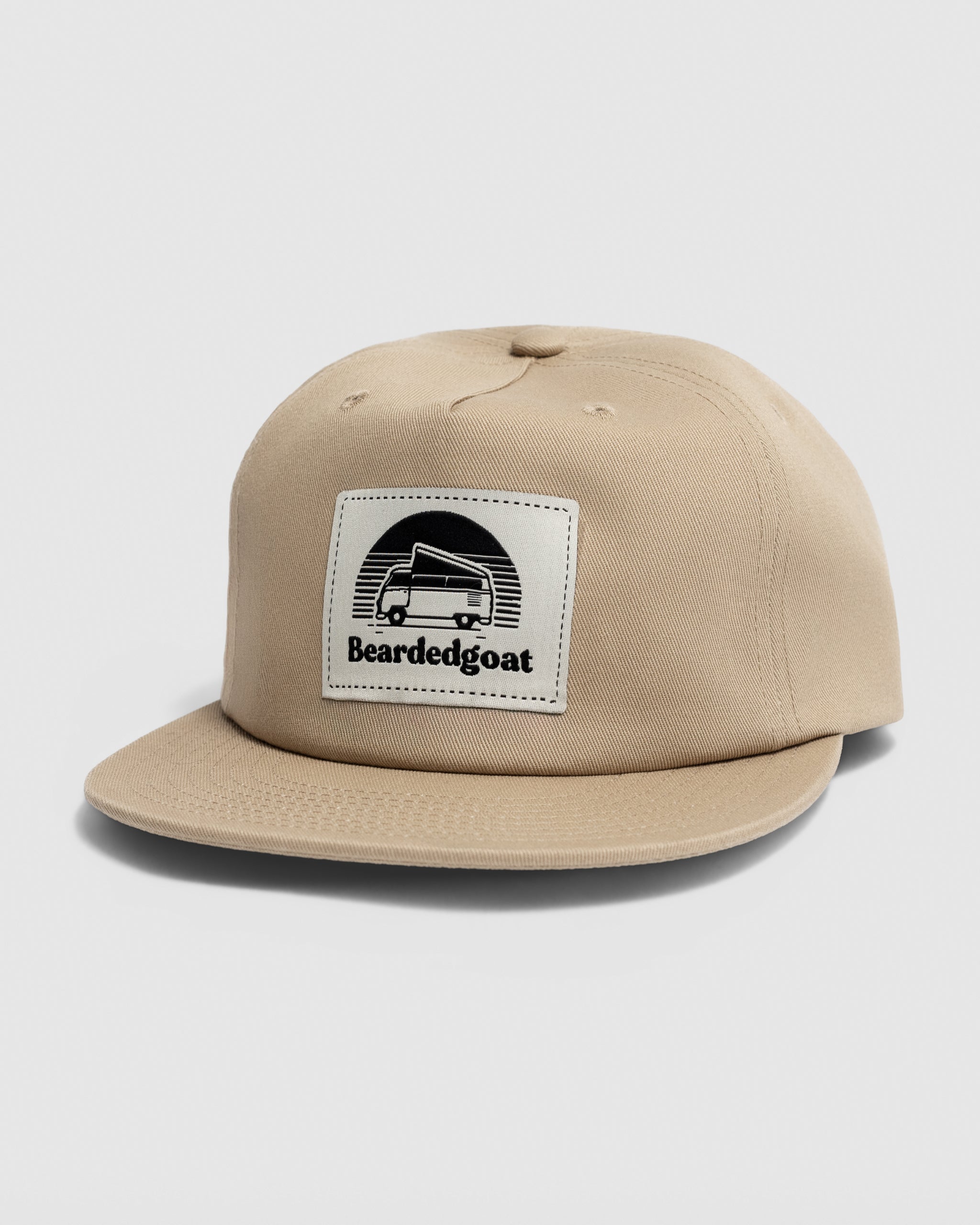 The Pop Up Label Hat - Sand by BEARDEDGOAT is a beige snapback with a flat brim, featuring a front patch with a van line drawing and “Beardedgoat” text—ideal for outdoor style and adventure enthusiasts.