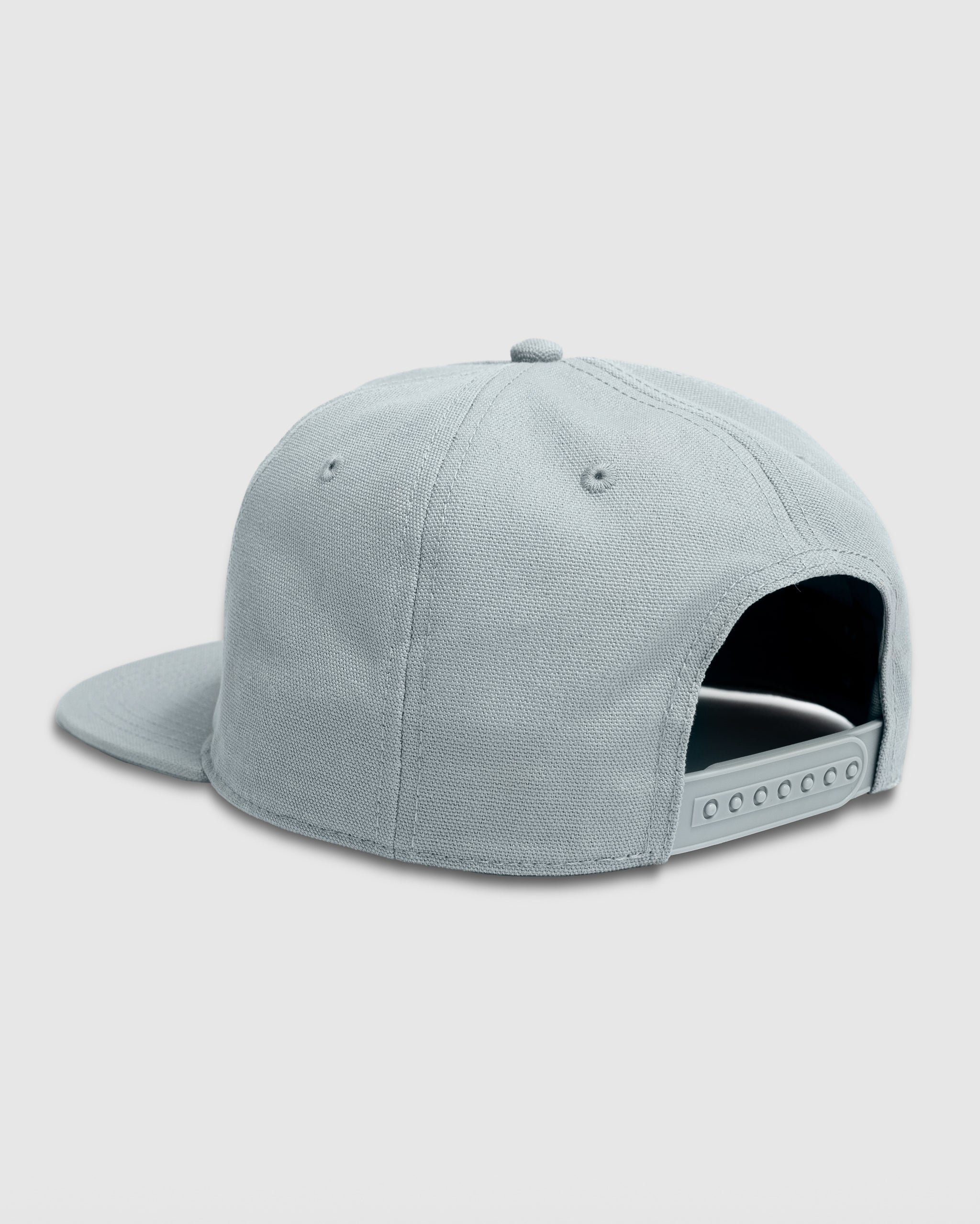 A BEARDEDGOAT Sunrise Label Hat in grey is displayed from the back, showing its adjustable snapback strap and flat brim. The adventure cap sits against a simple light background, blending outdoor style with practical design.