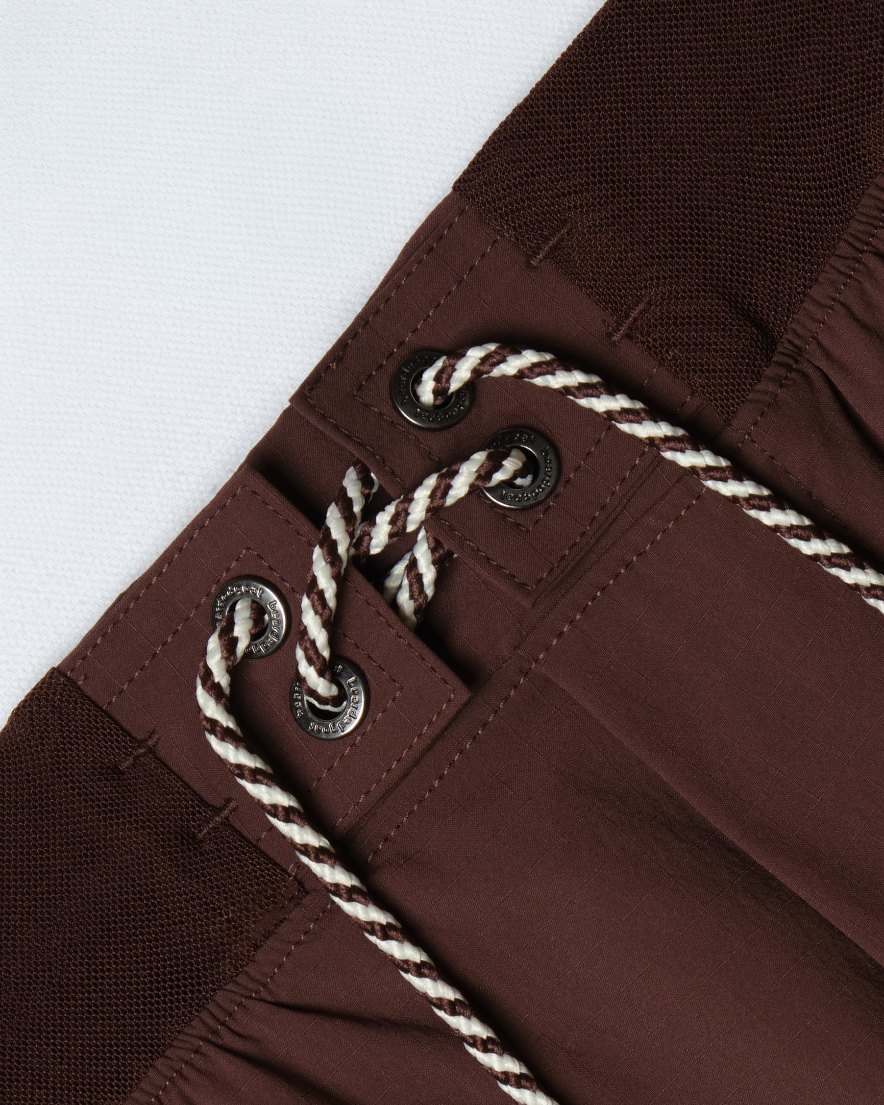 Close-up of the BEARDEDGOAT Men's Rambler Short waistband, highlighting a black and white braided drawstring through metal eyelets and a textured elastic band. Built for trail running with 4-way stretch for comfort.