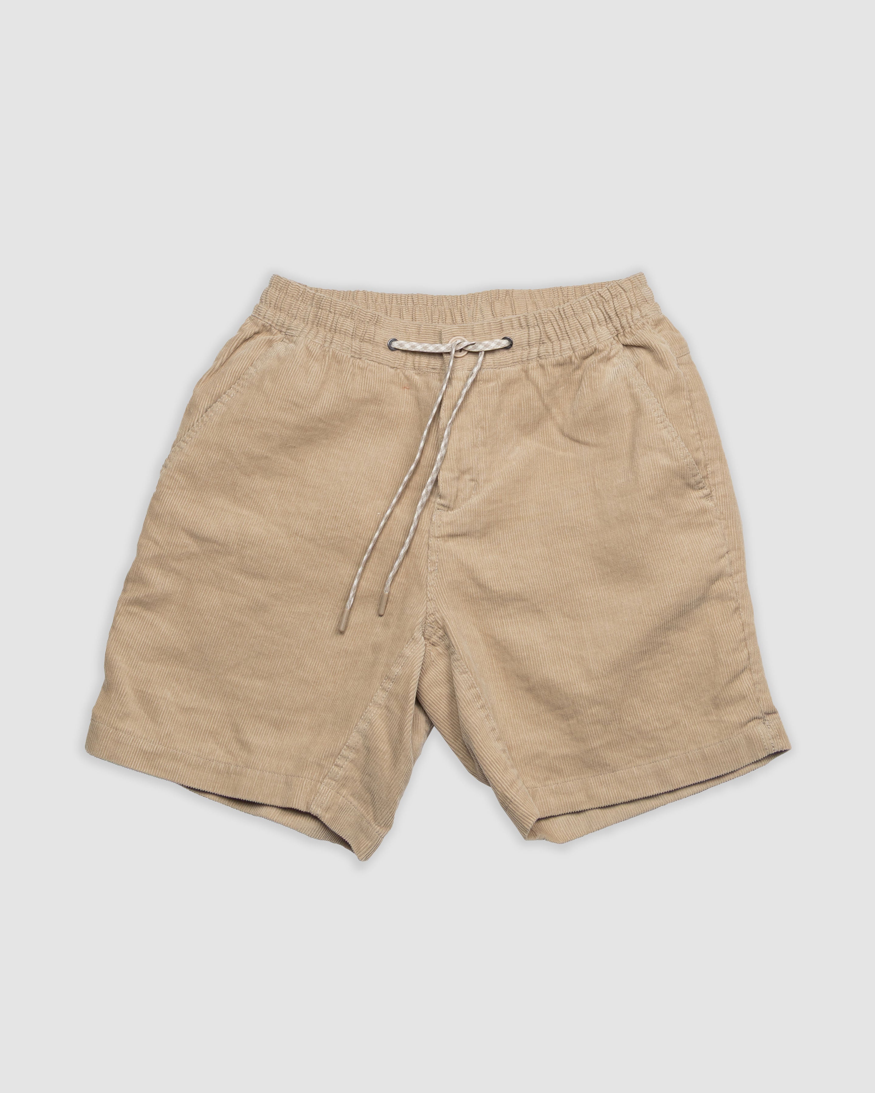 BEARDEDGOAT Mens Cord Short in beige corduroy, featuring vintage style, elastic waistband with white drawstring, and two side pockets, displayed flat on a light gray background.