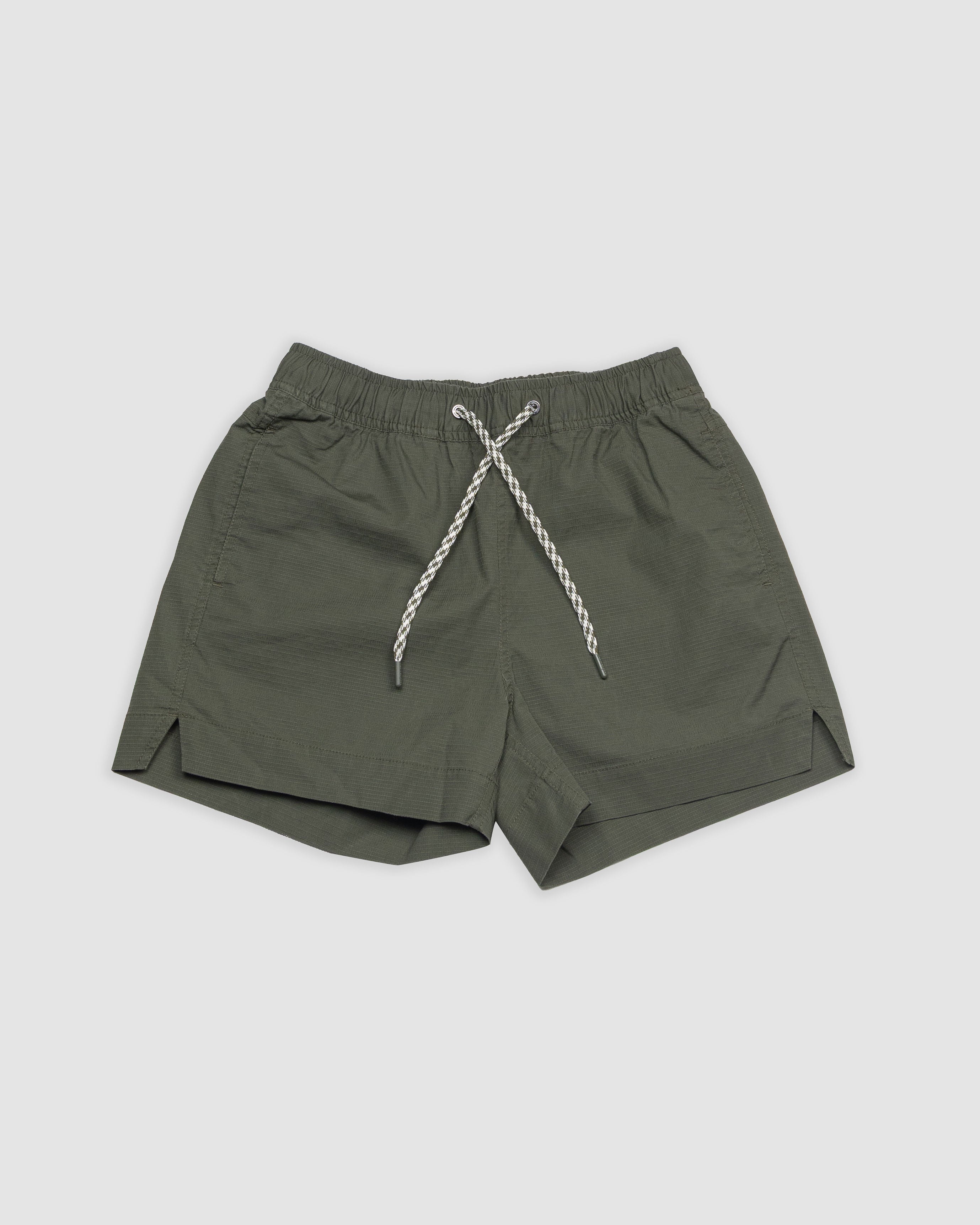 The BEARDEDGOAT Womens Canopy Short in olive green stretch cotton ripstop features an elastic waistband, white and gray rope drawstring, athletic fit, and small side slits on both legs, displayed flat on a light background.