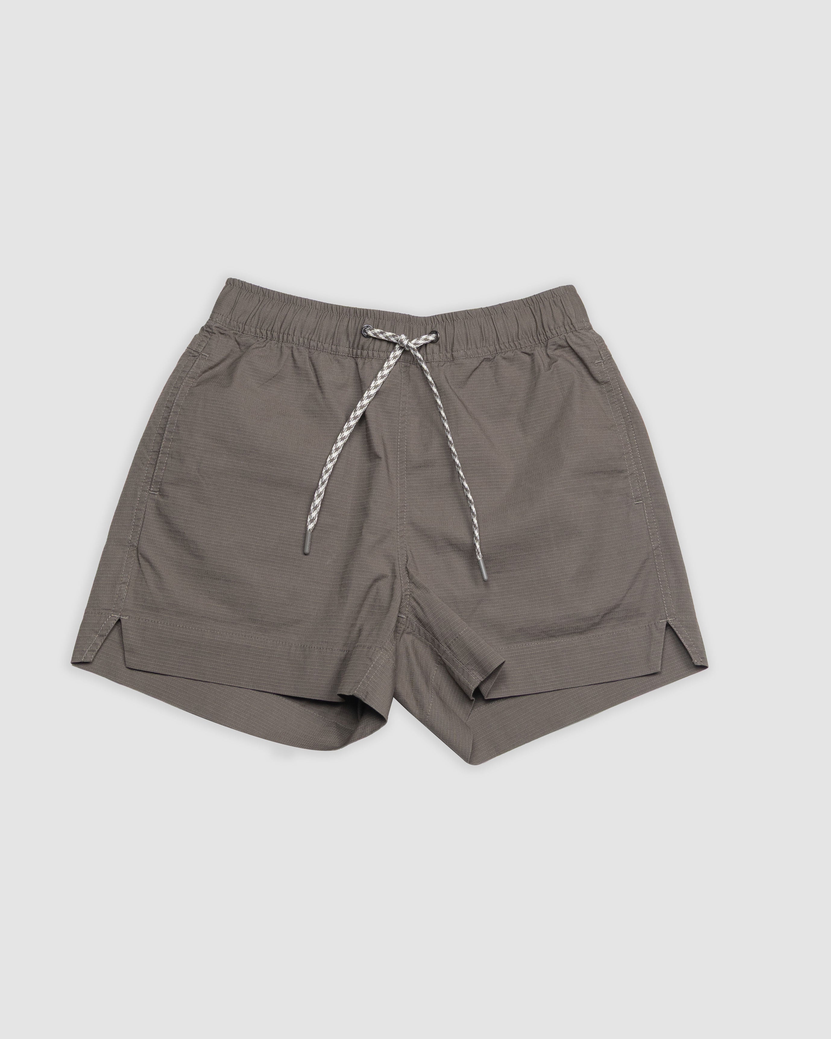 The BEARDEDGOAT Womens Canopy Short features an athletic fit, elastic waistband, side pockets, and small side slits, crafted from stretch cotton ripstop for breathable comfort. Shown in gray on a plain light background.