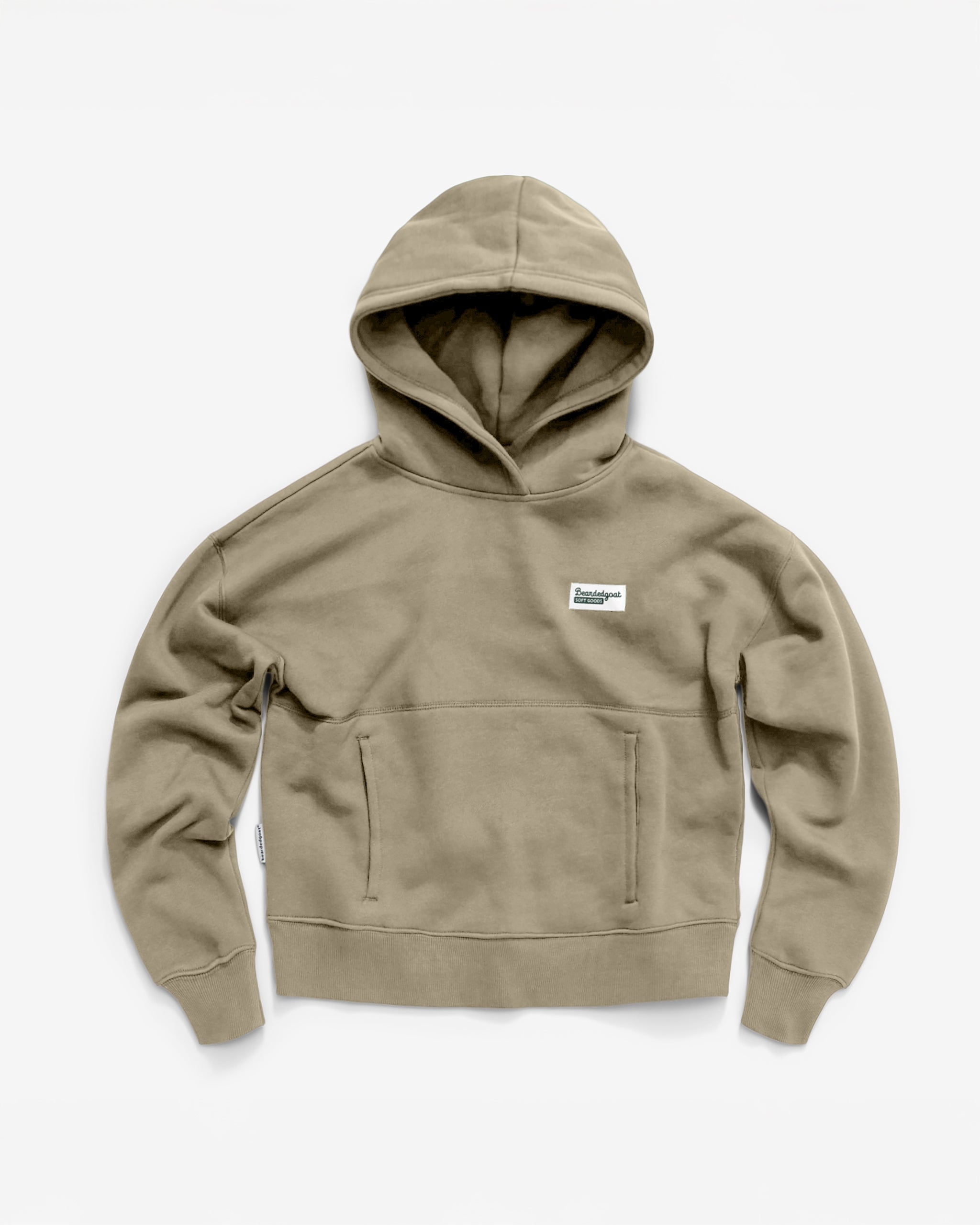 The Women's Overnight™ Hoodie by beardedgoat in khaki features a relaxed fit, premium cotton fleece, a front pocket, and a small rectangular chest logo patch, shown laid flat on a white background.