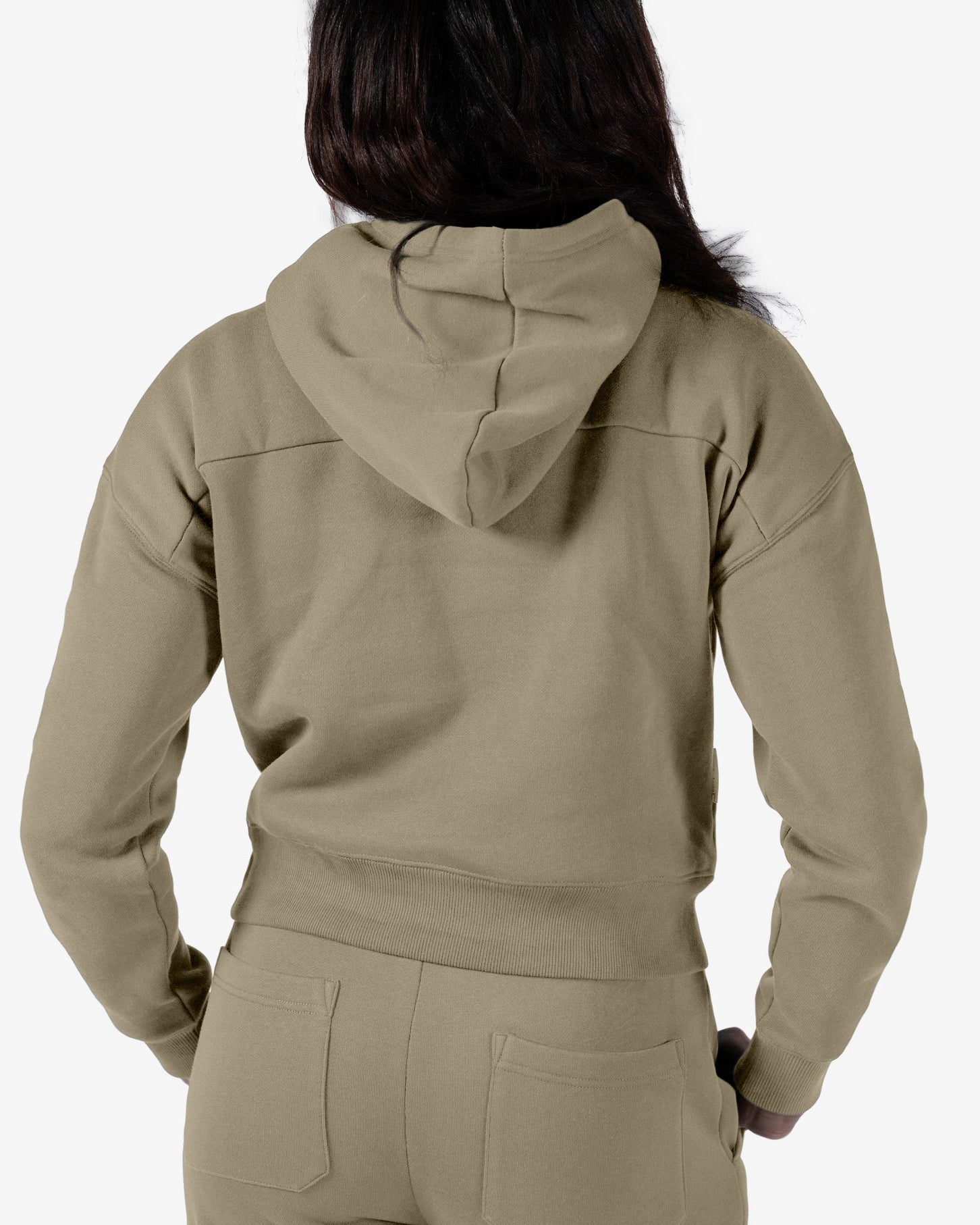 A woman with long dark hair, seen from behind, wears a relaxed fit khaki Women's Overnight™ Hoodie by beardedgoat and matching sweatpants, made from premium cotton fleece, against a plain light background.